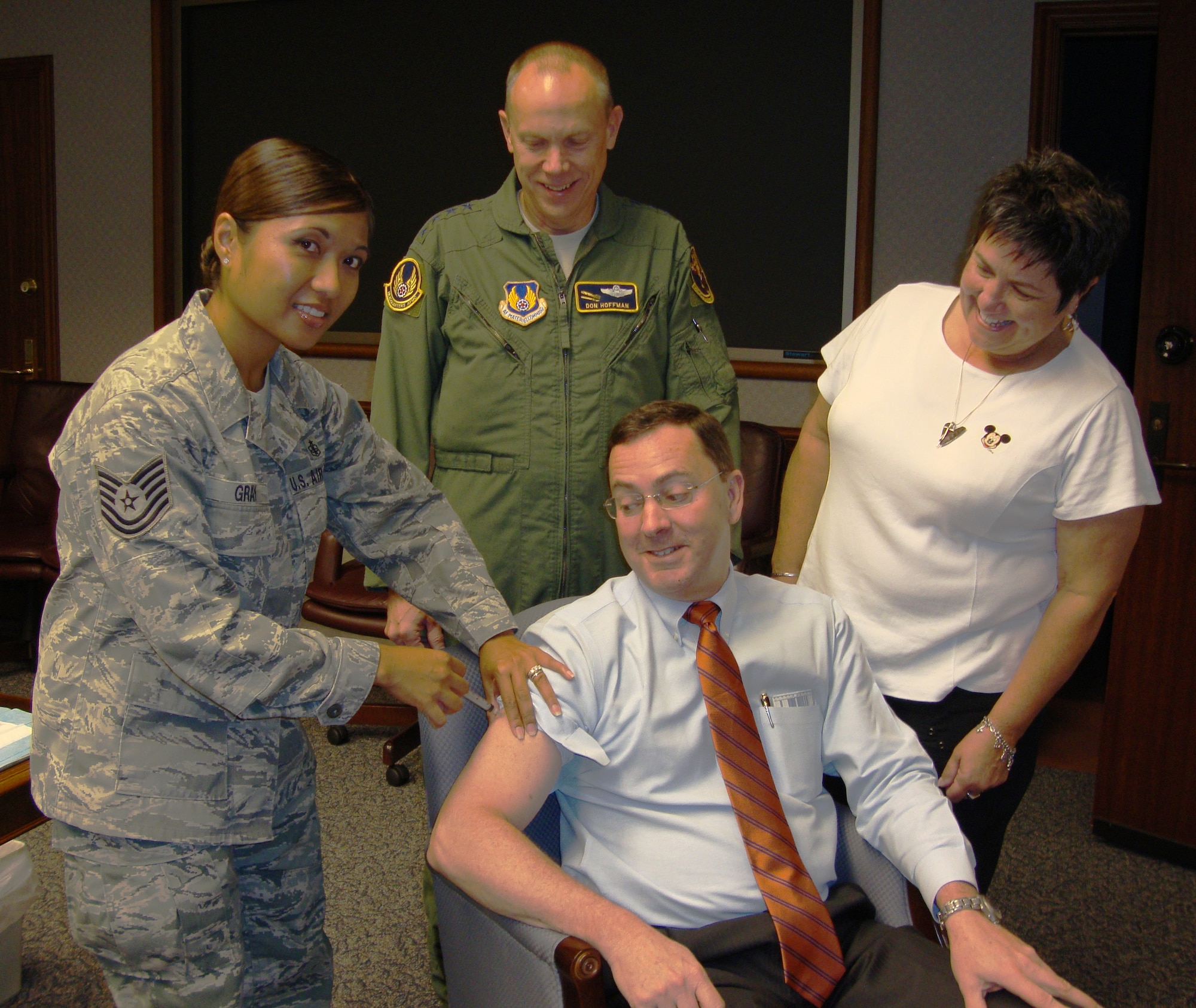 Dr. Steve Butler, Air Force Materiel Command executive director, received a flu shot Sept. 6 while AFMC Commander Gen. Donald Hoffman and his wife, Jackie, look on. The three gathered for their shots to help get spread the word that AFMC civilians will be offered flu shots in the coming the weeks. Mrs. Hoffman emphasized the importance of military family members getting their shots, as well. Dr. Butler's shot was administered by Technical Sgt. Victoria Gray of the 88th Medical Group at Wright-Patterson AFB. (U.S. Air Force photo/Ron Fry)