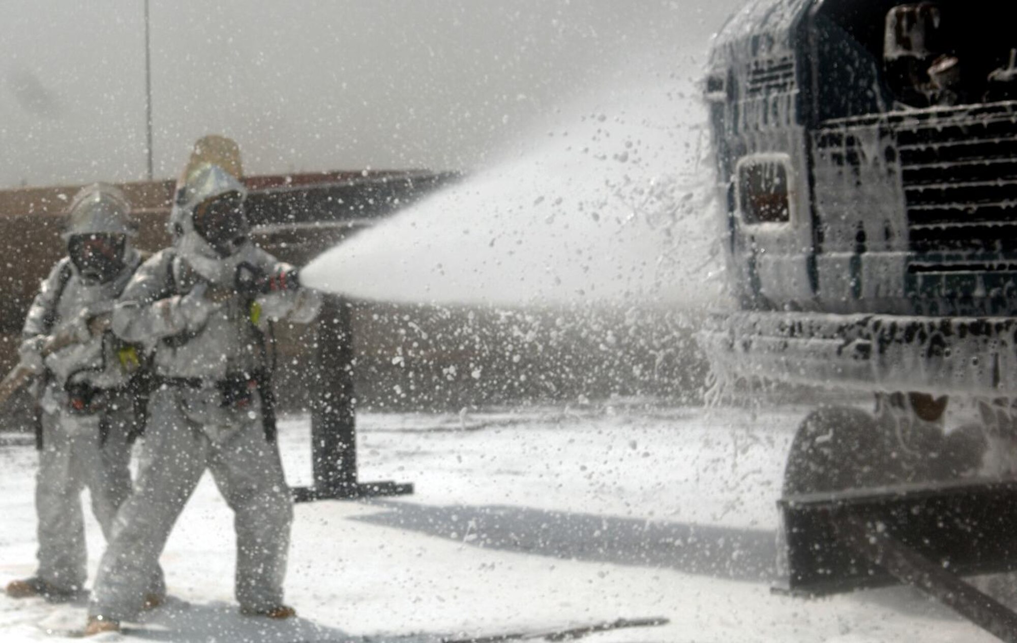 CAMP LEMONNIER, Djibouti -- Alfonso Bravo (left) and Siyaad Cheik, Camp Lemonnier Fire Department firefighters spray down a mock aircraft with AFFF foam concentrate during a training scenario, August 27. The Fire Department conducts routine training exercises to maintain skill proficiency. (U.S. Air Force photo by Senior Airman Jarad A. Denton) 