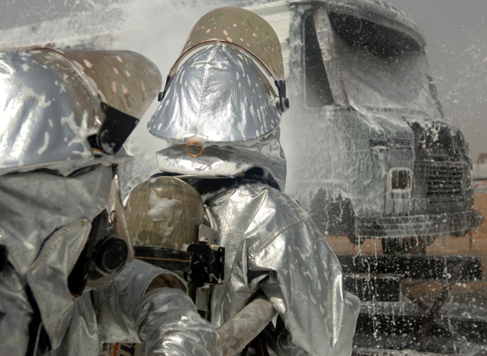 CAMP LEMONNIER, Djibouti -- Alfonso Bravo (left) and Siyaad Cheik, Camp Lemonnier Fire Department firefighters spray down a mock aircraft with AFFF foam concentrate during a training scenario, August 27. The Fire Department conducts routine training exercises to maintain skill proficiency. (U.S. Air Force photo by Senior Airman Jarad A. Denton) 