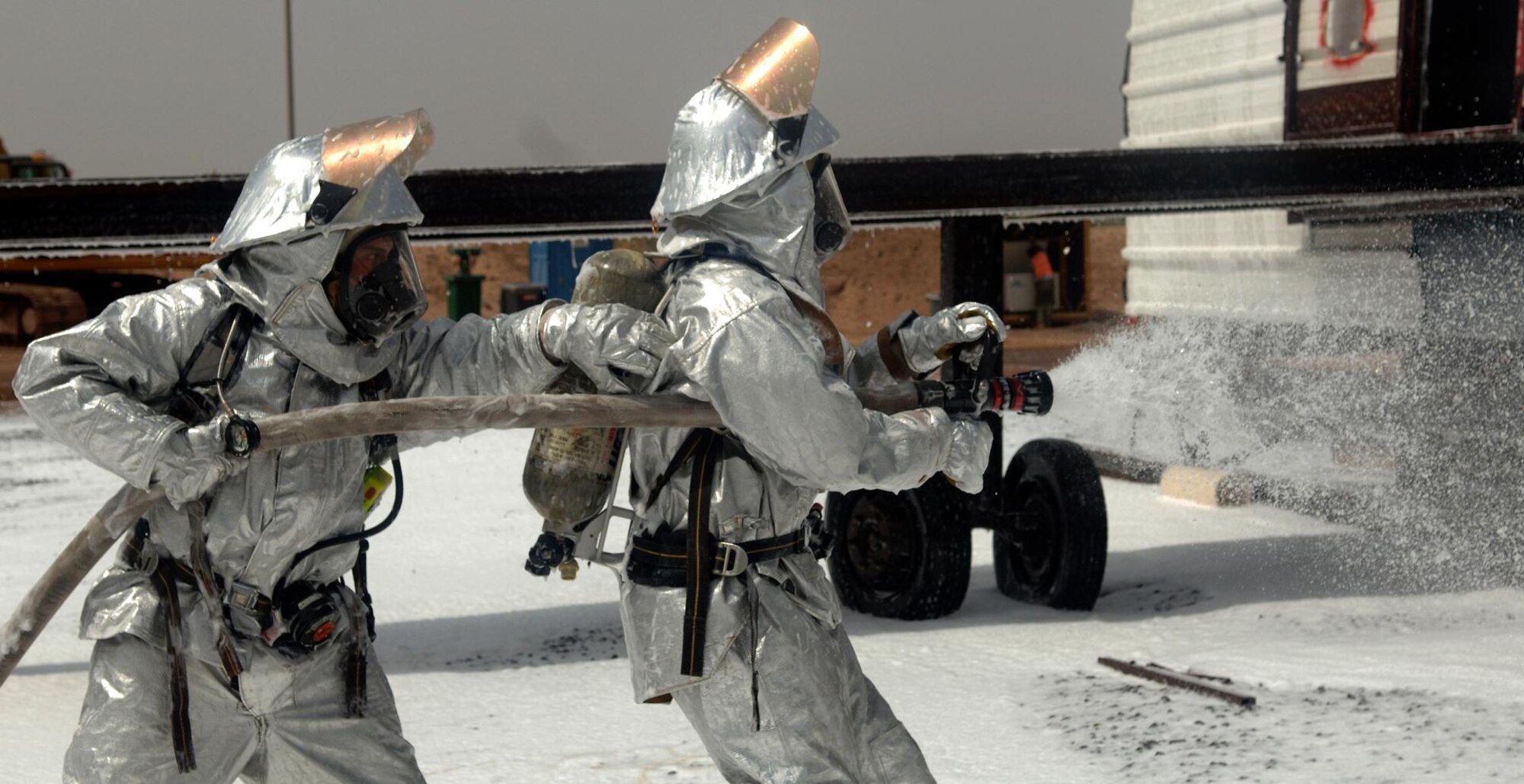 CAMP LEMONNIER, Djibouti -- Alfonso Bravo (left) and Siyaad Cheik, Camp Lemonnier Fire Department firefighters spray down a mock aircraft with AFFF foam concentrate during a training scenario, August 27. The Fire Department conducts routine training exercises to maintain skill proficiency. (U.S. Air Force photo by Senior Airman Jarad A. Denton) 