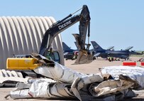 In preparation for a new tarmac and aircraft shelters, contract workers from ARK Wrecking tear down F-16 shelters at the 138th Fighter Wing, Oklahoma Air National Guard base in Tulsa, OK.  (U.S. Air Force Photo by Master Sergeant Preston Chasteen)
