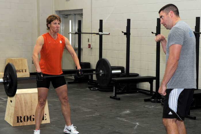 Master Sergeant Steven Hart motivates Barbara Snow as she performs "hang cleans" during the CrossFit instructor course at the Fitness and Sports Center Jan. 5, 2011. Members who attended the CrossFit instructor course performed three rounds of 20 repetitions of "box jumps", "wall balls" and "hang cleans" which consisted of 60 total repetitions per exercise, 180 for workout total. Hart is the 628th Communications Squadron first sergeant and Snow is assigned to the 628th Air Base Wing wing plans office. (U.S. Air Force photo/Staff Sgt. Marie Brown)