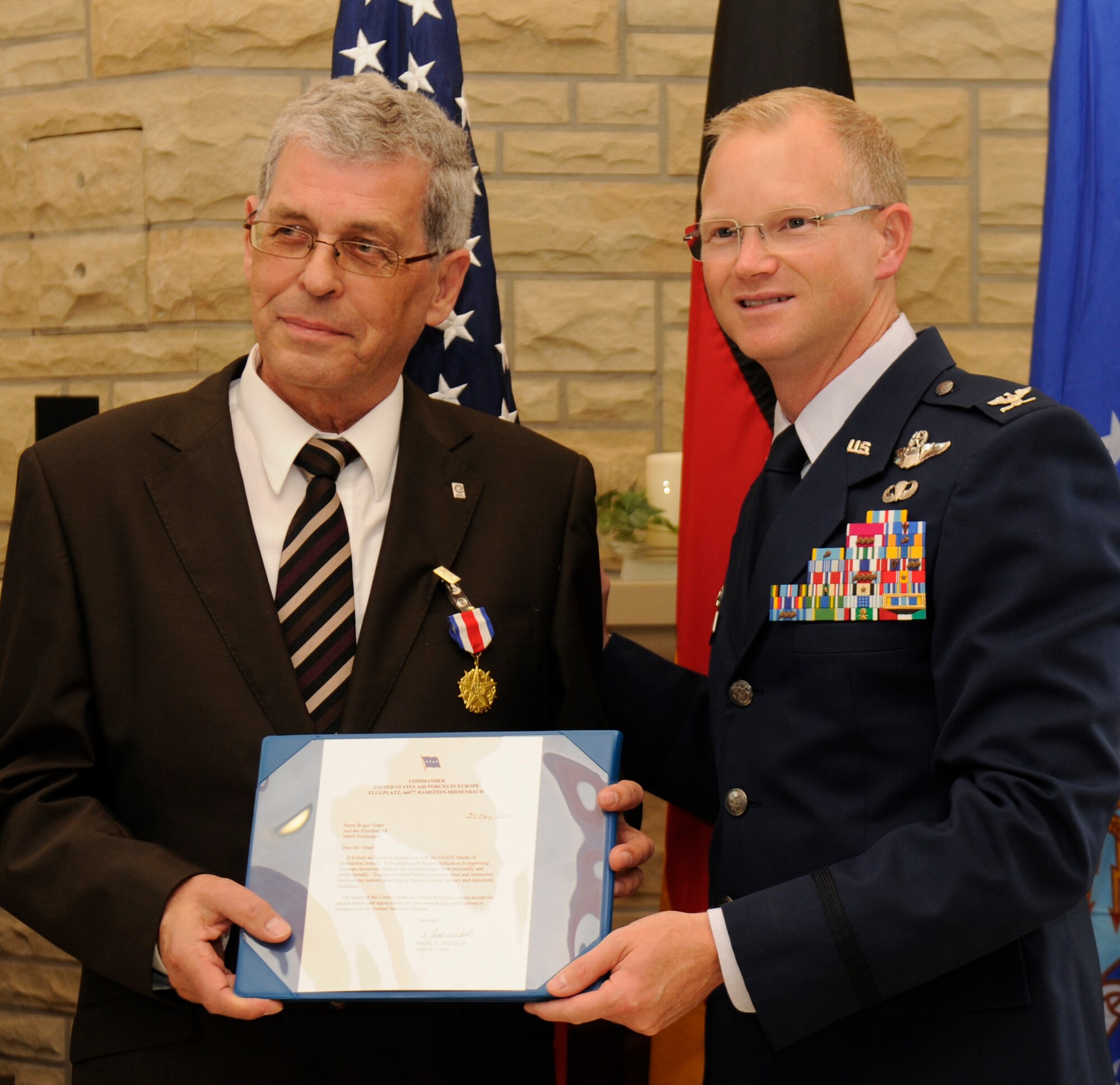 SPANGDAHLEM AIR BASE, Germany -- Col. Christopher Weggeman, 52nd Fighter Wing commander, presents Mr. Roger Graef, commissioner for the Bitburg-Prüm County, with the U.S. Air Forces in Europe Medal of Distinction at Club Eifel here Sept. 6. The USAFE Medal of Distinction is the highest medal awarded to host nation partners. According to his citation, Graef has been a positive influence in the advancement of German-American relations and has created closer ties between USAFE Airmen and host- nation citizens. (U.S. Air Force photo/Airman 1st Class Brittney Frees)