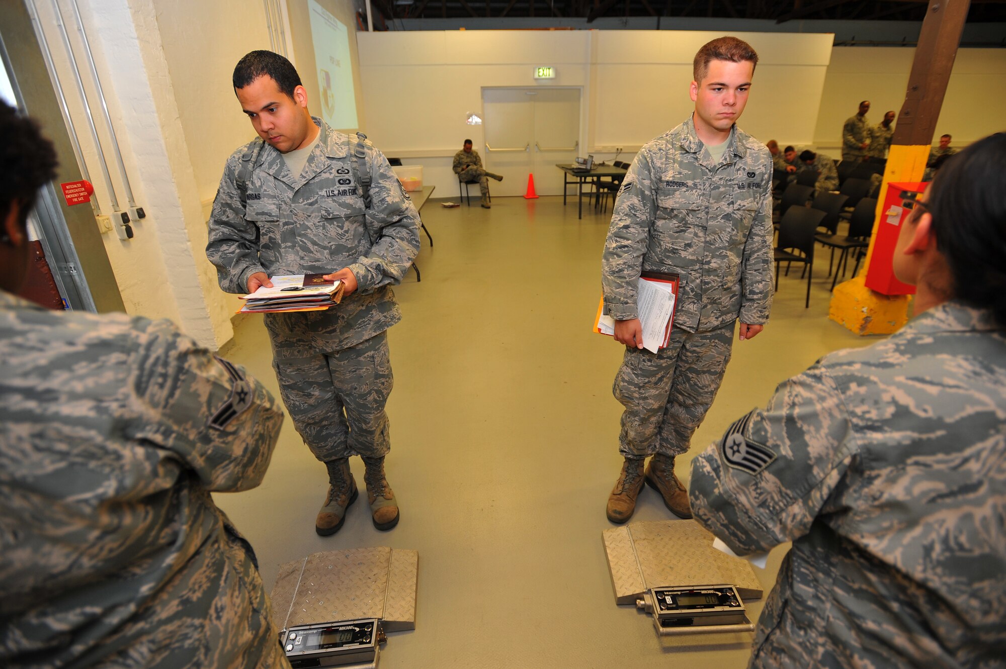 SPANGDAHLEM AIR BASE, Germany – Staff Sgt. Angel Vargas, left, and Airman 1st Class Timothy Rodgers, both assigned to the 606th Air Control Squadron, line up to weigh-in during a personnel deployment function line here Sept. 6. The PDF line consists of various base agencies that ensure deploying members have all necessary paperwork and checklists completed before leaving. (U.S Air Force photo/Airman 1st Class Dillon Davis)