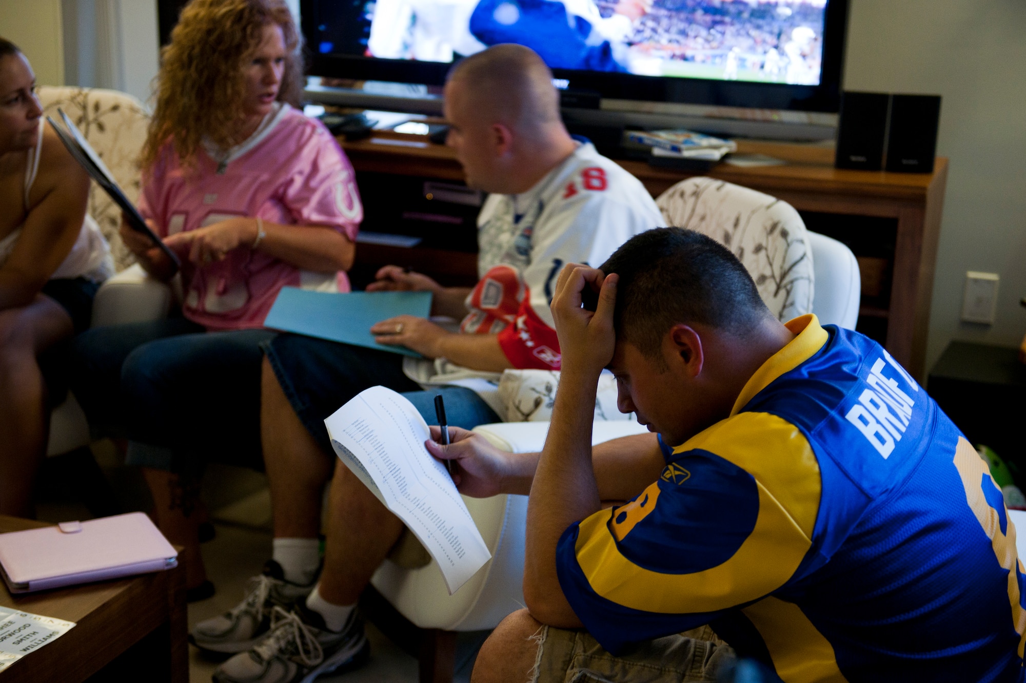 Participants review statistics while selecting players during a fantasy football draft Sept. 2, 2011, at Incirlik Air Base, Turkey. Fantasy drafts can be online, but a group of Incirlik Airmen, spouses and contractors decided to participate in a live draft. This type offers participants an opportunity to socialize and build camaraderie. (U.S. Air Force photo by Tech. Sgt. Michael B. Keller/Released)