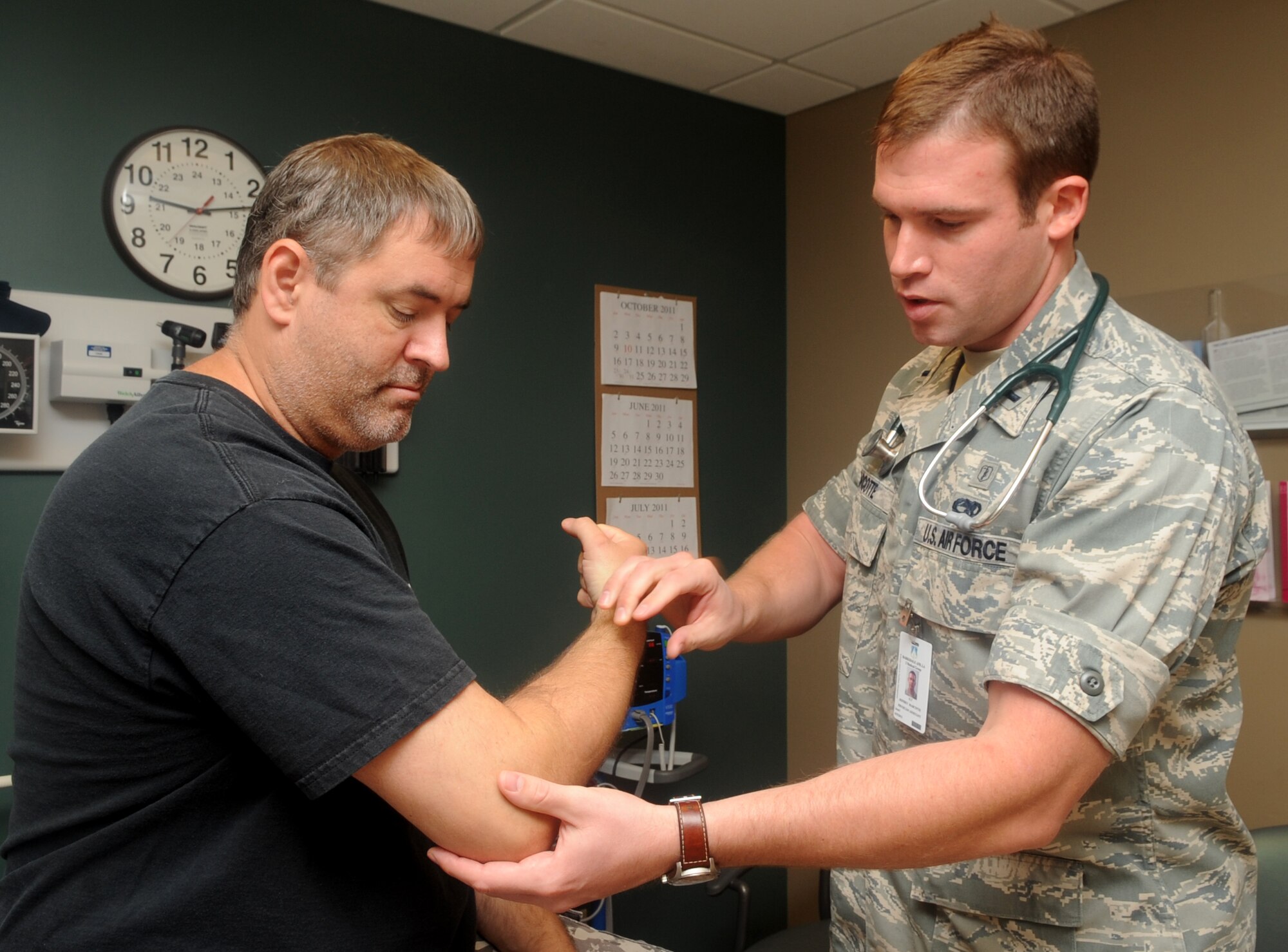 1st Lt. Jeffrey Marcotte, 2nd Medical Operations Squadron physician assistant, examines Allen Dinsmore's elbow on Barksdale Air Force Base, La., Sept 8. Each physician in the family health clinic sees between 19 and 21 patients daily. (U.S. Air Force photo/Senior Airman Kristin High) (RELEASED)