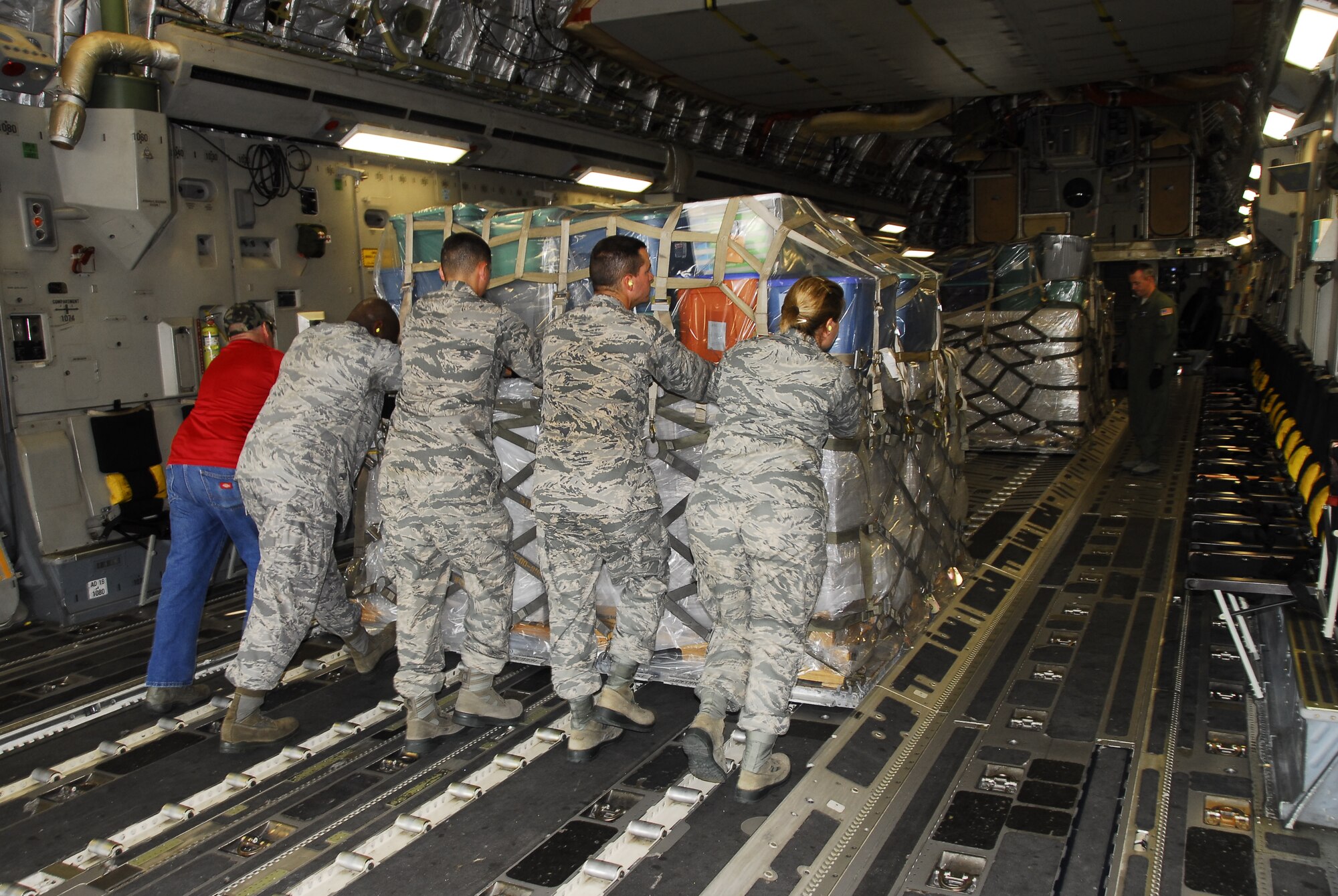 From left, Master Sgt. David Greer, Staff Sgt. Antoine Armor, Airmen Basic Tyler Cancel, Heath Ezelle and Melissa Erickson of the 908th Airlift Wing’s 25 Aerial Port Squadron push the second of five pallets loaded with humanitarian supplies into the cargo hold of a C-17 Globemaster III from JRB Charleston, S.C. (Air Force photo by Gene H. Hughes)