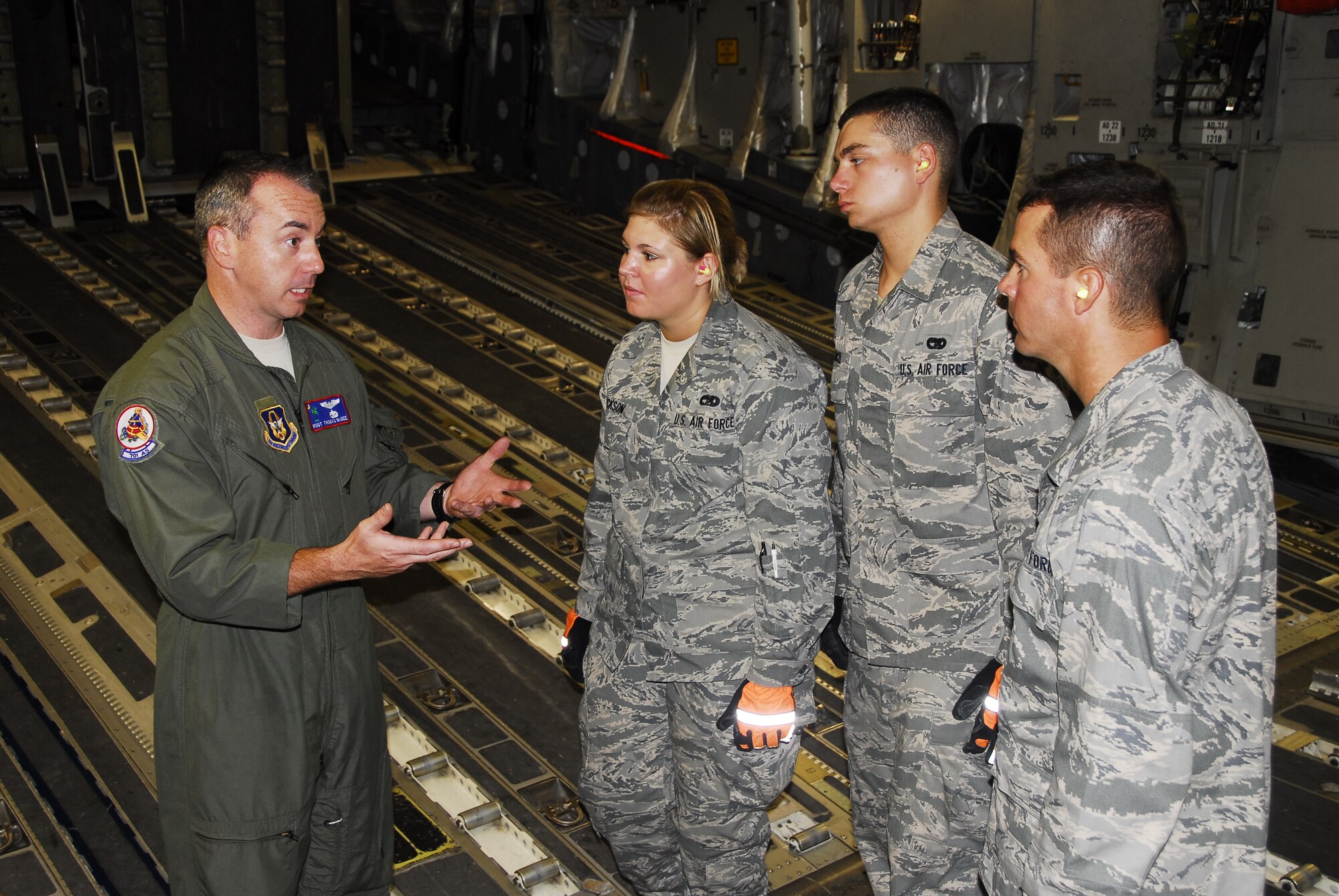 Basic Airmen Airmen Melissa Erickson, Tyler Cancel and Heath Ezelle of the 908th Airlift Wing listen as Master Sgt. Thomas McGee, a loadmaster with the 315th Airlift Wing, describes the challenges of the c-17 Globemaster III. The three Airmen, recently graduated from tech school, had just finished helping load the aircraft with five pallets of humanitarian cargo, their first real-world operation. (Air Force photo by Gene H. Hughes)