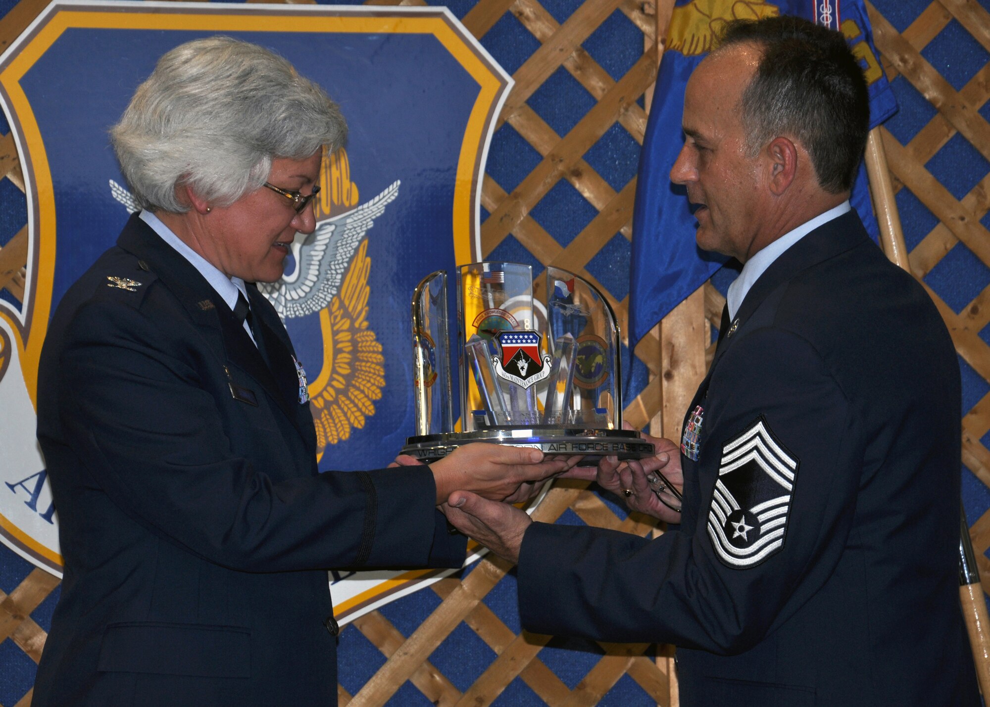 WRIGHT-PATTERSON AIR FORCE BASE, Ohio - Chief Master Sgt. Aaron Mouser, 445th Maintenance Group superintendent, presents Col. Anna Schulte, 445th Maintenance Group commander, a going away gift Aug. 13. The present was designed and handcrafted by the 445th Structural Repair Shop as a going away gift to Schulte, who has taken an assignment as commander of the 403rd Maintenance Group at Keesler Air Force Base, Miss. (U.S. Air Force photo/Staff Sgt. Amanda Duncan)