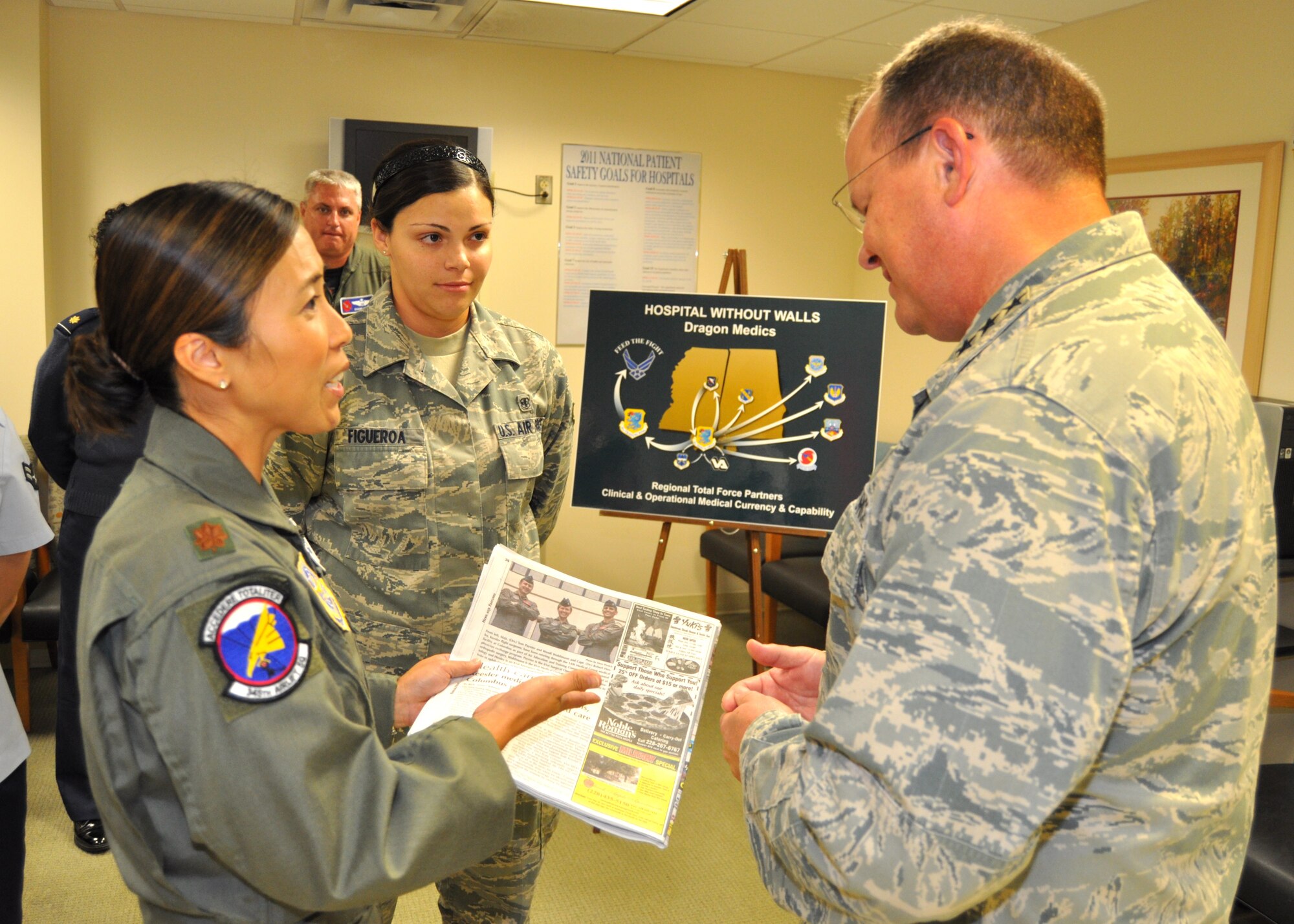 Maj. (Dr.) Marie Han, left, 81st Aerospace Medicine Squadron flight medicine flight commander, shows Lt. Gen. (Dr.) Charles Green, Air Force surgeon general, a recent Keesler News article that described how Keesler flight surgeons have been assisting Columbus Air Force Base, Miss., as part of a unique physician exchange program. General Green visited the Keesler Hospital Aug. 29 while attending the Society of Air Force Clinical Surgeons Symposium at Biloxi’s IP Casino Resort and Spa. Airman 1st Class Ashley Figueroa, a flight medicine flight medical technician, looks on.  (U.S. Air Force photo by Steve Pivnick)