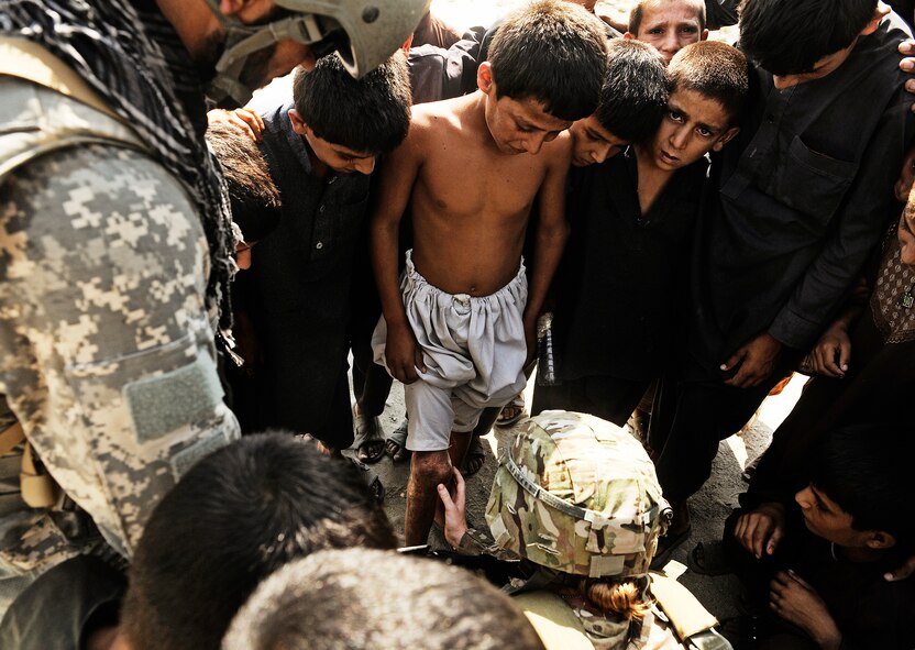 Tech. Sgt. Angela Pollard examines a child's injured knee during a mentoring neighborhood patrol Sept. 5, 2011, in the Laghman province of Afghanistan. Laghman Provincial Reconstruction Team members joined Afghan National Police members on a patrol to teach them to conduct foot patrols through villages and talk to the locals, gathering information first hand. Pollard is a medic attached to the Laghman PRT. (U.S. Air Force photo/Staff Sgt. Ryan Crane)