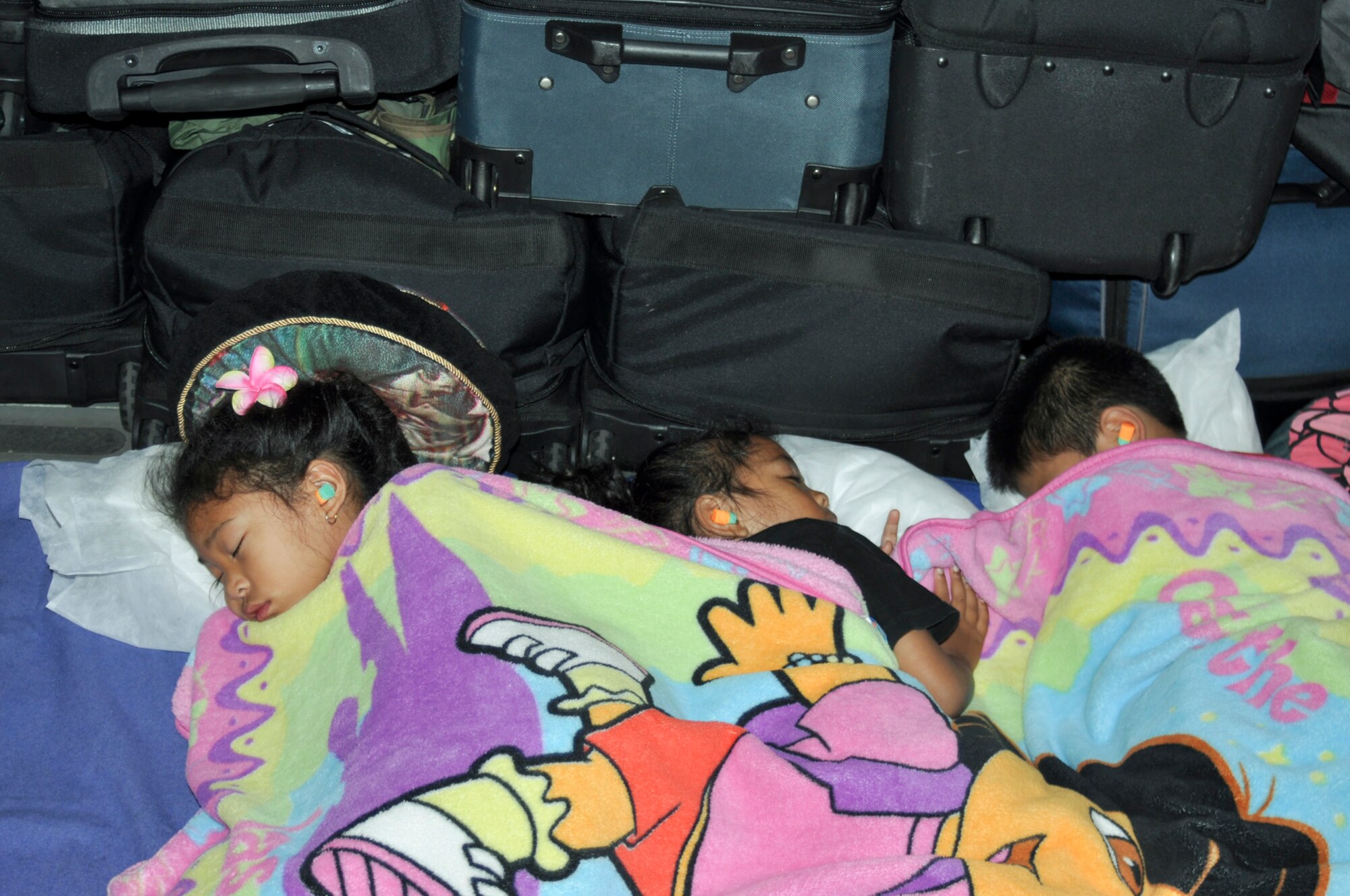 Three militarychildren sleep soundly aboard a C-17 Globemaster III on a flight between Hawaii and South Korea, Aug. 25, 2011.  The children flew Space-A with their mother to visit their father, who was on TDY orders.  The aircraft was from the 729th Airlift Squadronn at March Air Reserve Base, Calif. (U.S. Air Force photo / Master Sgt. Linda Welz)