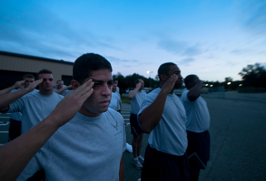 U.S. Air Force Master Sgt. Jason Castro, 820th Combat Operation Squadron aircrew flight equipment craftsman, and fellow Airmen render salutes during the playing of reveille at Moody Air Force Base Ga., Sept. 6, 2011. Following reveille, Airmen from the 820th Base Defense Group participated in a physical training program they call Sergeant Rock.  The PT program focuses on pushups and sit ups and is geared to help Airmen pass their PT test. (U.S. Air Force photo by Airman 1st Class Joshua Green/Released)  
