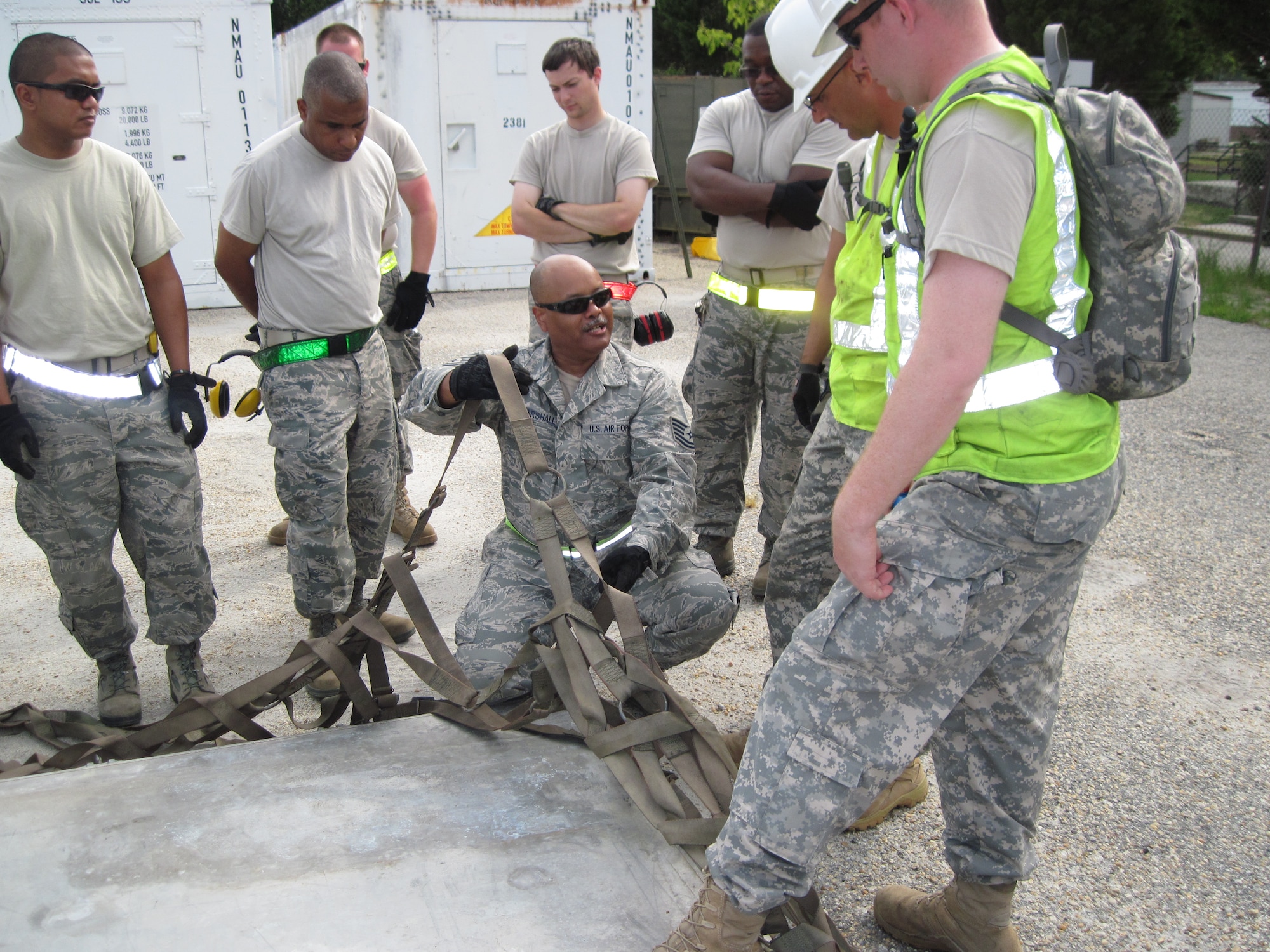 Tech. Sgt. Clarence Marshall, (kneeling) 71st Aerial Port Squadron aerial porter, demonstrates the proper placement of a pallet side net to participants in a joint contingency-training exercise at Fort Eustis, Va.  Aug. 4, 2011. Participating units included the 71st APS, the 633rd Logistics Readiness Squadron and the 690th Rapid Port Opening Element.  (U.S. Air Force Photo by Chief Master Sgt. Chris Alston/Released)