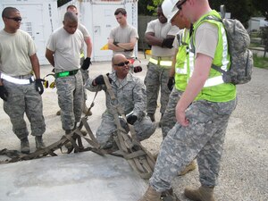 Tech. Sgt. Clarence Marshall, (kneeling) 71st Aerial Port Squadron aerial porter, demonstrates the proper placement of a pallet side net to participants in a joint contingency-training exercise at Fort Eustis, Va.  Aug. 4, 2011. Participating units included the 71st APS, the 633rd Logistics Readiness Squadron and the 690th Rapid Port Opening Element.  (U.S. Air Force Photo by Chief Master Sgt. Chris Alston/Released)