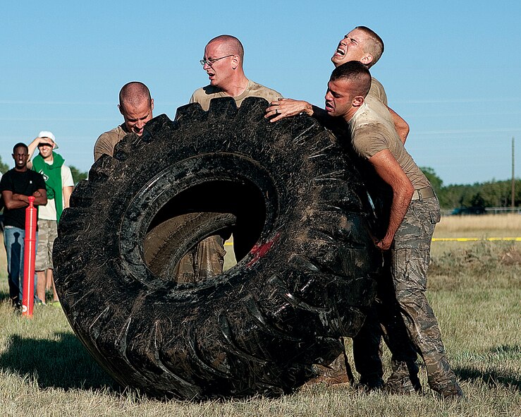 Senior Airman Andrew Albritton, Senior Airman Tyler Whaley, Airman 1st Class Paul Cameron and Airman 1st Class Kody Crosson, all with the 790th Missile Security Forces Squadron Response Force 2, flip a tire end-over-end while competing in the "Team Pain" event during Crow Creek Challenge here Aug. 25. (U.S. Air Force photo by Matt Bilden)