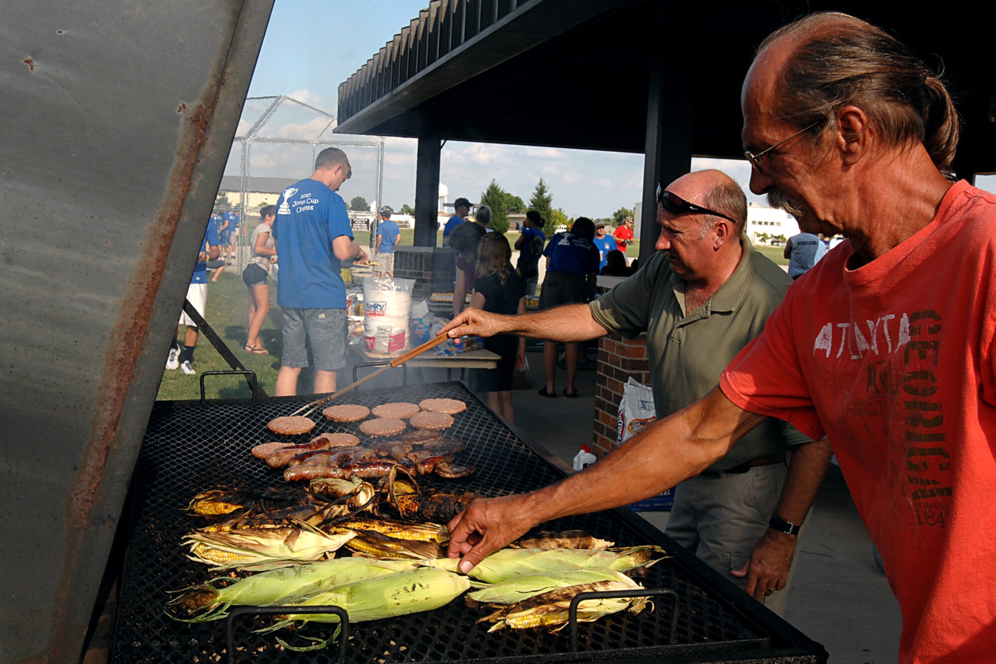 GRISSOM AIR RESERVE BASE, Ind.-- Chief master Sgt. Alan Edgerley, 434th Operations Support Squadron  operations resource manager chief; and David Youker, 434th Civil Engineering computer specialist, slave away at the grill to feed the hungry appetites of the players, family and friends during the 5th Annual Jovanovich Cup Aug 13. Every year the Fightin' Red Tags and the Dark Side battle it out for a trophy and bragging rights. This year the Red Tags edged the Dark Siders, 13-12. The event is held in memory of Lt. Col. George Jovanovich who died in a car accident in March 2006. (U.S. Air Force photo/Senior Airman Jami K. Lancette) 