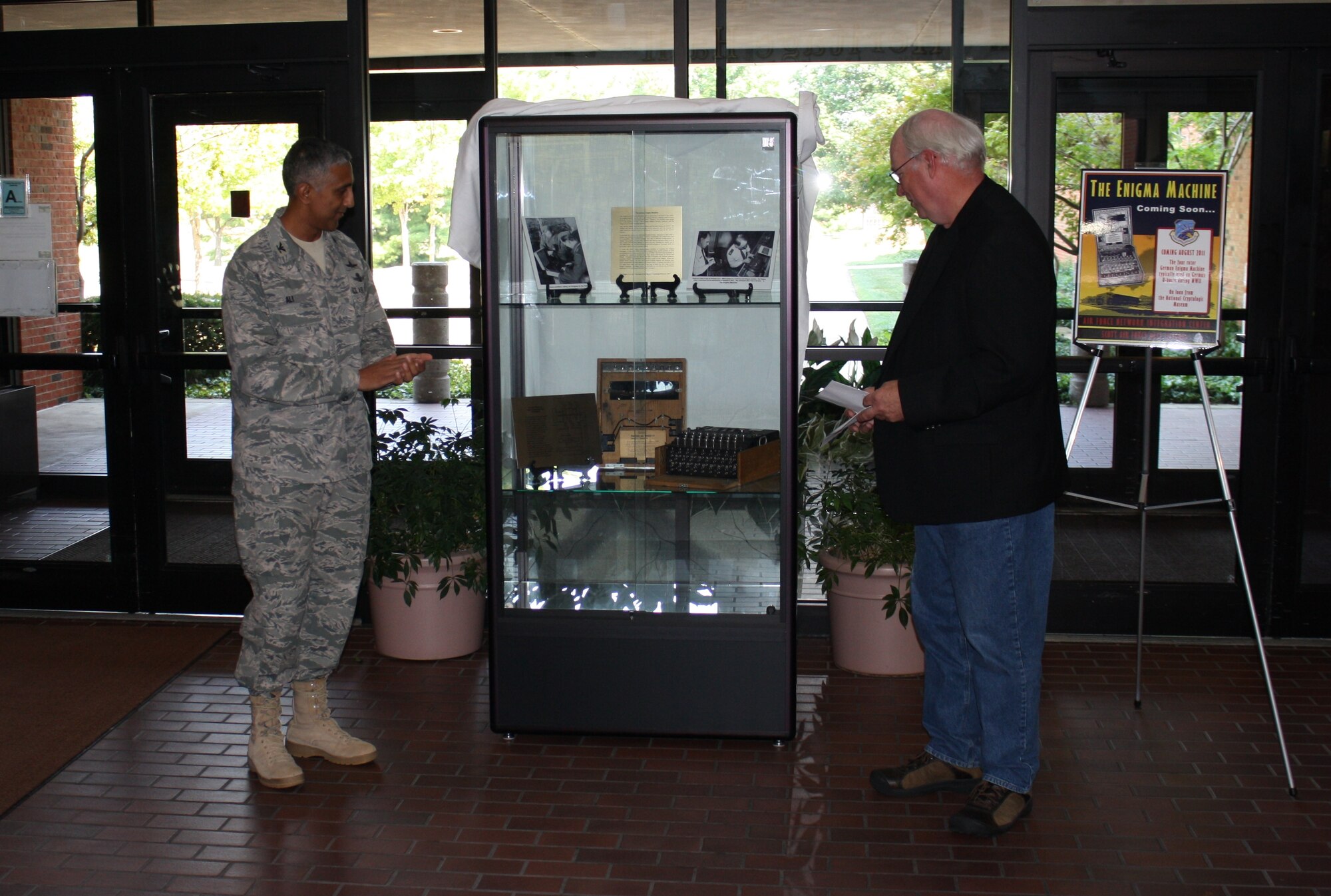 SCOTT AIR FORCE BASE, Ill. – Col. Rizwan “Riz” Ali, Air Force Network Integration Center Commander, and Tyson Joye, AFNIC’s Museum Curator, unveil the Engima machine display during a ceremony here Sept. 1.  The Enigma is on indefinite loan to AFNIC from the National Cryptologic Museum.  (U.S. Air Force photo/Travis Nuckolls)