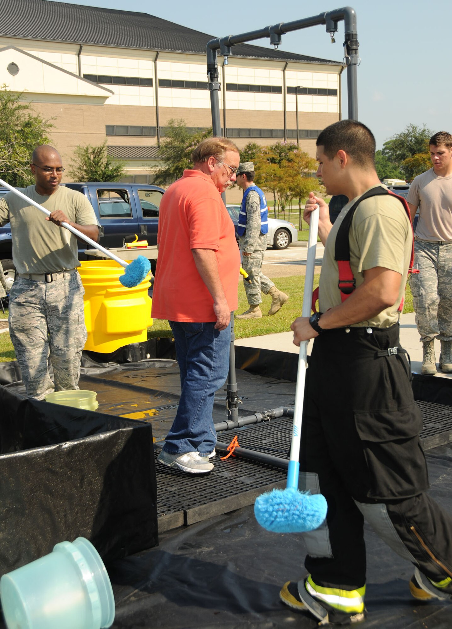 Staff Sgts. Nicholas Young, left, and Jeremiah Ramos, right, Keesler firefighters, simulate scrubbing down Dale Riggins in the decontamination area set up outside Matero Hall. Riggins, 81st Training Support Squadron, was one of the people who had contact with the contaminated package during a force protection exercise Aug. 31.  (U.S. Air Force photo by Kemberly Groue)