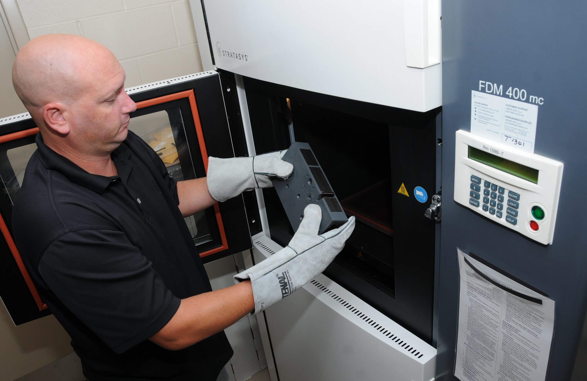 Heath Harris, a fabricator in the 81st Training Support Squadron trainer development
flight, removes an object from the printing chamber and inspects it for blemishes. This object was printed using fused deposition modeling in the Stratasys 3-D printer. Trainer development has two 3-D printers used in the production of parts, prototypes and replicas of real items. These valuable assets are used in creating training simulators to help Keesler and other bases perform their training missions more effectively and economically. (U.S. Air Force photo by Kemberly Groue)