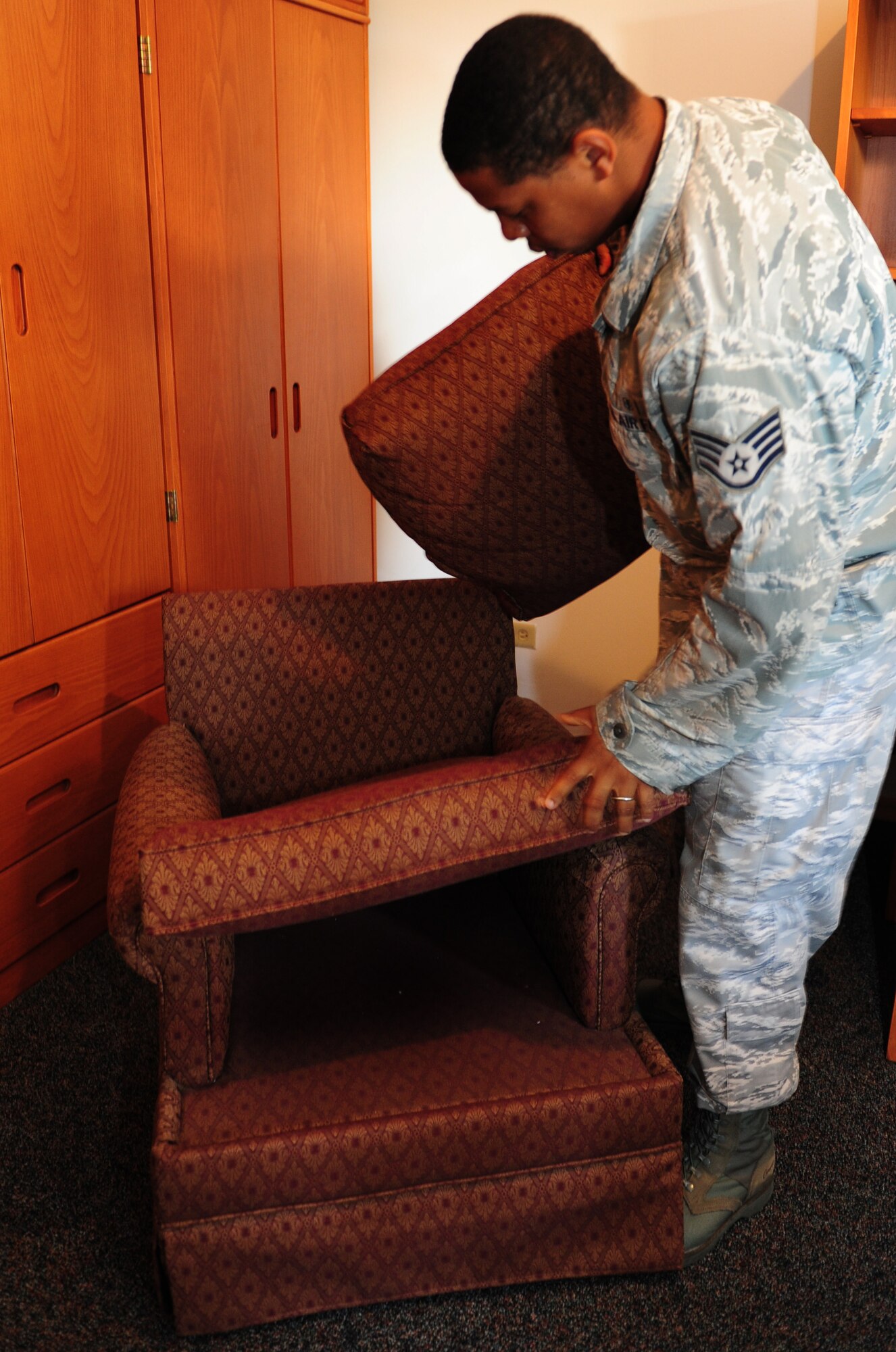 Staff Sgt. Marcus Pierce, 39th Civil Engineer Squadron dorm manager, checks for cleanliness underneath a chair cushion during a final outprocessing inspection in an Airman’s dorm room Sept. 7, 2011, at Incirlik Air Base, Turkey. Dorm managers conduct dormitory room inspections and unaccompanied housing inspections with people inprocessing and outprocessing the base. (U.S. Air Force photo by Senior Airman Anthony Sanchelli/Released) 