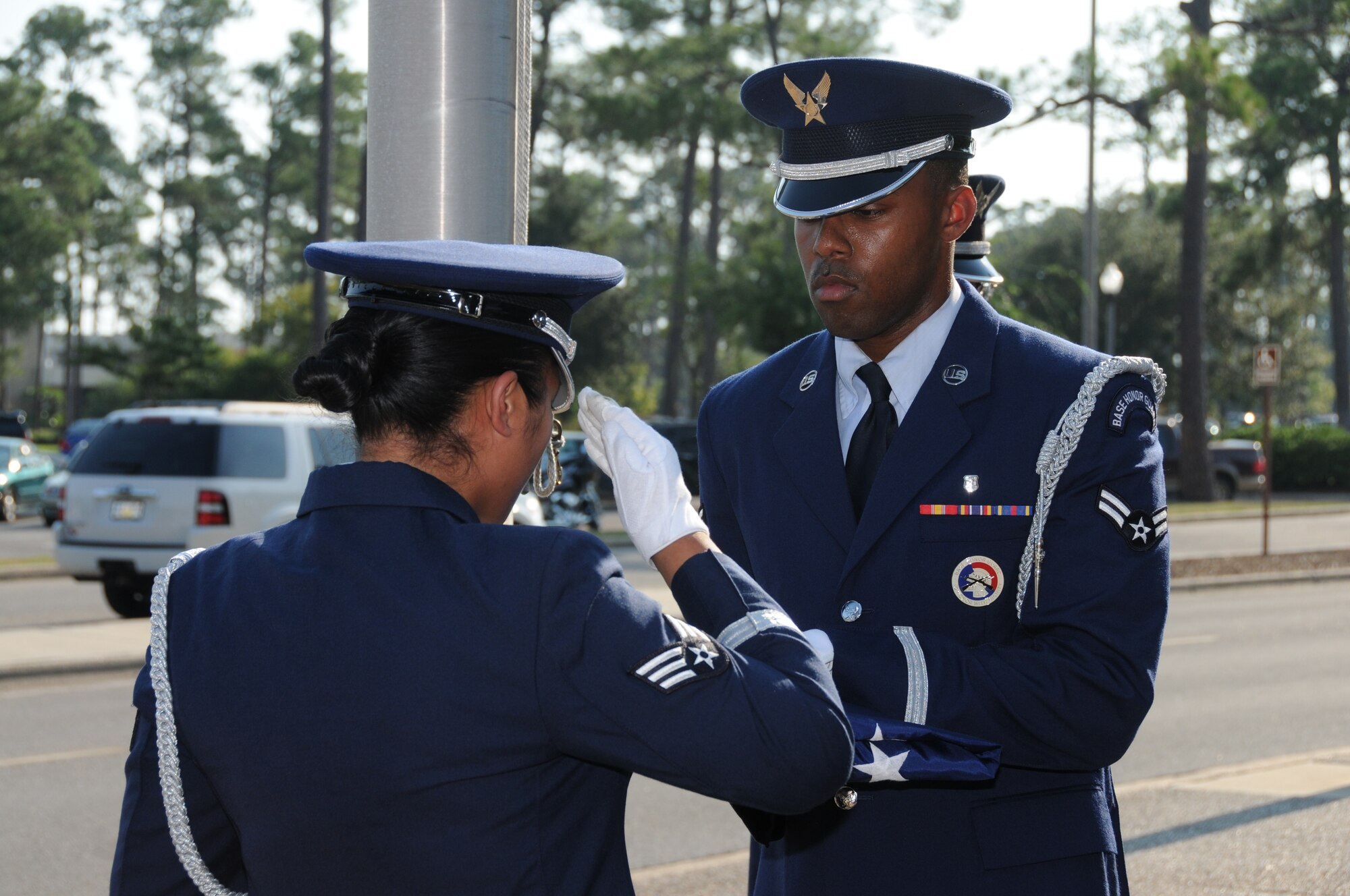 Members of the Keesler AFB Honor Guard fold the U.S. flag during a special retreat ceremony conducted Aug. 30 in front of the Keesler Hospital to honor former 81st Medical Group Commander retired Brig. Gen. (Dr.) Dan Locker, visible at the right side of the flag.  General Locker led the "Dragon Medics"  from July 1997-June 2002.  This was his first visit to the hospital since his  August 2002 retirement.  He was in the area attending the Society of Air Force Clinical Surgeons Symposium held at Biloxi's IP Casino Resort and Spa.  Honor guard members are, from left:  Airmen 1st Class Terrance Hill, 81st Aerospace Medicine Squadron; and Kayle Potts Parker, 81st Medical Operations Squadron; and Senior Airman Eriqa Cortez, 81st Diagnostics and Therapeutics Squadron.  (U.S. Air Force photo by Kemberly Groue)
