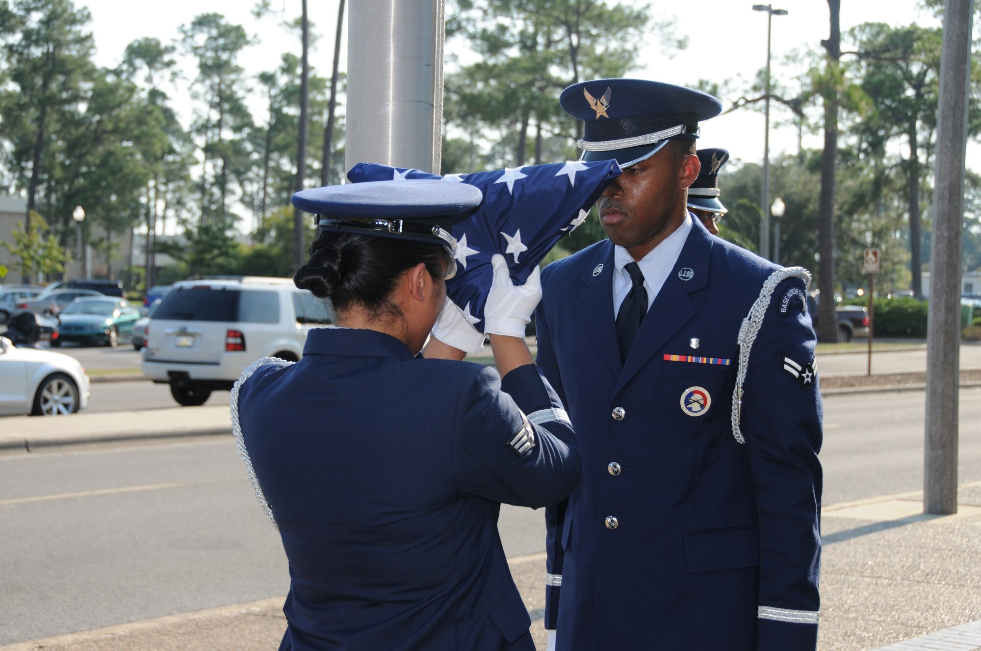 Members of the Keesler AFB Honor Guard fold the U.S. flag during a special retreat ceremony conducted Aug. 30 in front of the Keesler Hospital to honor former 81st Medical Group Commander retired Brig. Gen. (Dr.) Dan Locker, visible at the right side of the flag.  General Locker led the "Dragon Medics"  from July 1997-June 2002.  This was his first visit to the hospital since his  August 2002 retirement.  He was in the area attending the Society of Air Force Clinical Surgeons Symposium held at Biloxi's IP Casino Resort and Spa.  Honor guard members are, from left:  Airmen 1st Class Terrance Hill, 81st Aerospace Medicine Squadron; and Kayle Potts Parker, 81st Medical Operations Squadron; and Senior Airman Eriqa Cortez, 81st Diagnostics and Therapeutics Squadron.  (U.S. Air Force photo by Kemberly Groue)
