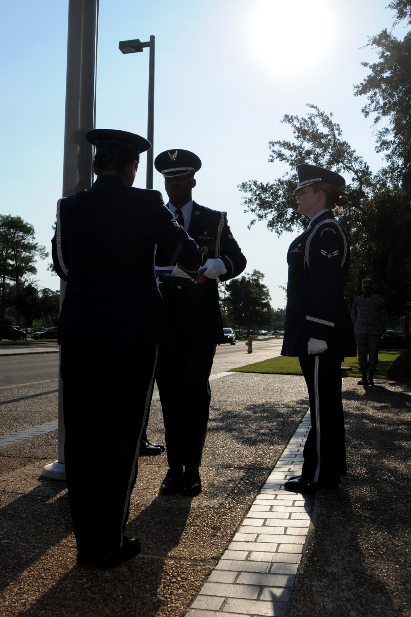Members of the Keesler AFB Honor Guard fold the U.S. flag during a special retreat ceremony conducted Aug. 30 in front of the Keesler Hospital to honor former 81st Medical Group Commander retired Brig. Gen. (Dr.) Dan Locker, visible at the right side of the flag.  General Locker led the "Dragon Medics"  from July 1997-June 2002.  This was his first visit to the hospital since his  August 2002 retirement.  He was in the area attending the Society of Air Force Clinical Surgeons Symposium held at Biloxi's IP Casino Resort and Spa.  Honor guard members are, from left:  Airmen 1st Class Terrance Hill, 81st Aerospace Medicine Squadron; and Kayle Potts Parker, 81st Medical Operations Squadron; and Senior Airman Eriqa Cortez, 81st Diagnostics and Therapeutics Squadron.  (U.S. Air Force photo by Kemberly Groue)
