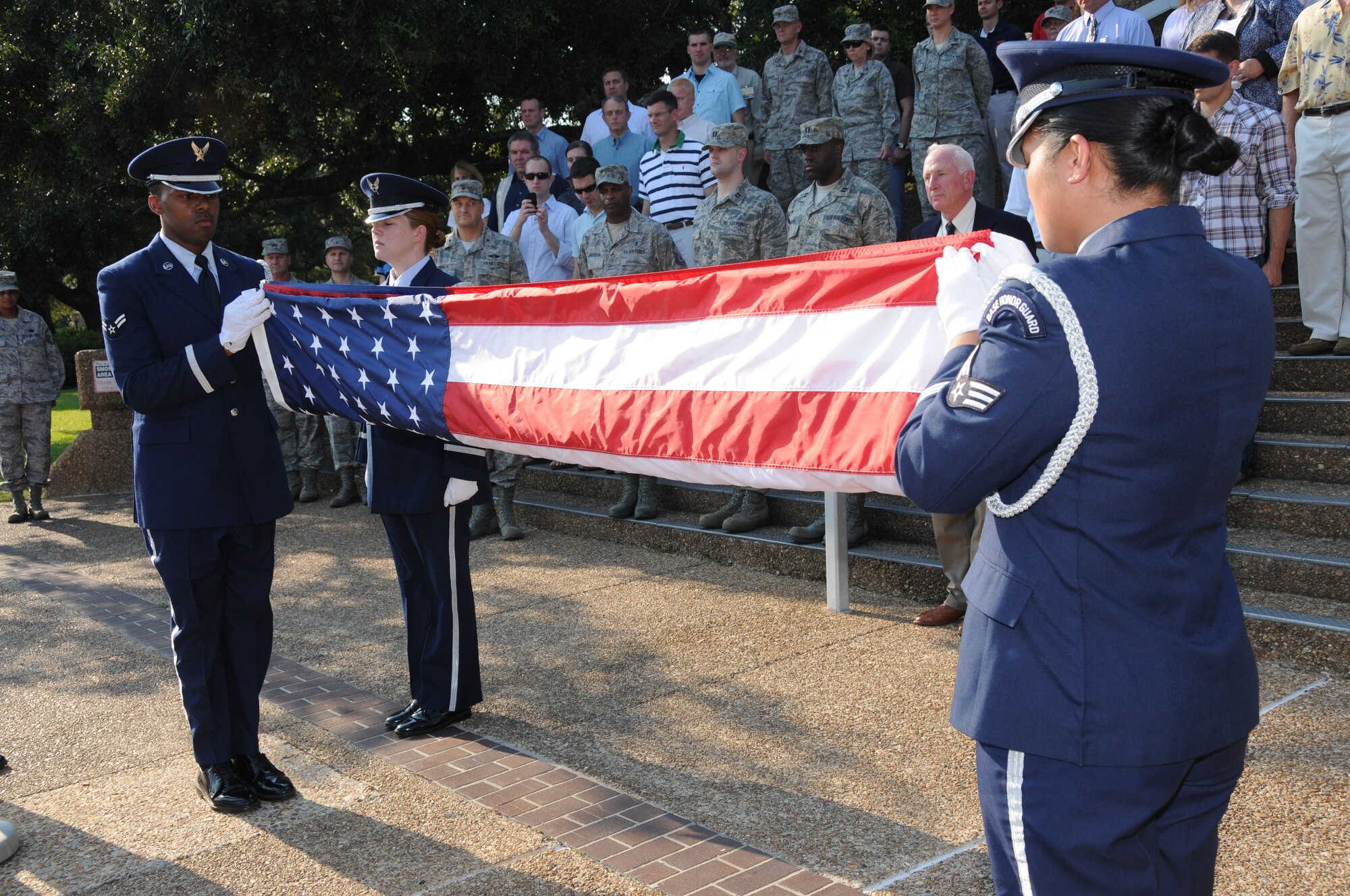 Members of the Keesler AFB Honor Guard fold the U.S. flag during a special retreat ceremony conducted Aug. 30 in front of the Keesler Hospital to honor former 81st Medical Group Commander retired Brig. Gen. (Dr.) Dan Locker, visible at the right side of the flag.  General Locker led the "Dragon Medics"  from July 1997-June 2002.  This was his first visit to the hospital since his  August 2002 retirement.  He was in the area attending the Society of Air Force Clinical Surgeons Symposium held at Biloxi's IP Casino Resort and Spa.  Honor guard members are, from left:  Airmen 1st Class Terrance Hill, 81st Aerospace Medicine Squadron; and Kayle Potts Parker, 81st Medical Operations Squadron; and Senior Airman Eriqa Cortez, 81st Diagnostics and Therapeutics Squadron.  (U.S. Air Force photo by Kemberly Groue)
