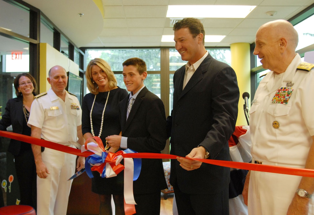 Hockey legend Mario Lemieux, his wife, Nathalie, and son, Austin, join Navy Vice Adm. John M. Mateczun, far right, commander of Joint Task Force National Capital Region Medical, and Navy Rear Adm. Matthew Nathan, far left, commander of Walter Reed National Military Medical Center, in cutting the ribbon to officially open Austin’s Warrior Playroom in a wounded warrior barracks on Naval Support Activity Bethesda, Md., Sept. 7, 2011. The playroom offers children care while their parents attend medical appointments. DOD photo by Elaine Sanchez