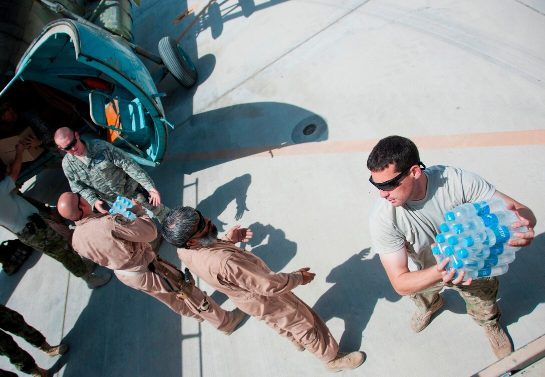 U.S. Air Force Tech. Sgt. Jason Fowler, right, grabs a pack of water bottles to load into an Afghan Army MI-17 helicopter on Kandahar Airfield, Afghanistan, Sept. 5, 2011. Fowler is a  aircraft electrical and environmental advisor assigned to the 35th Aircraft Maintenance Squadron, deployed from McConnell Air Force Base, Kansas.