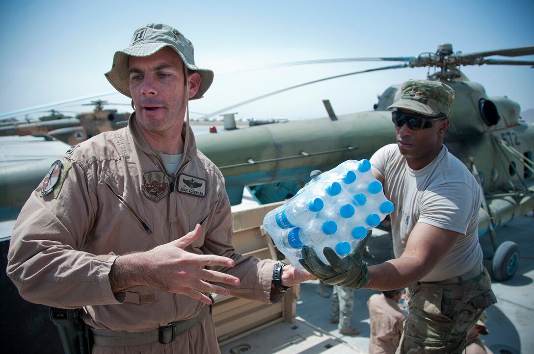 U.S. Air Force Capt. Adam Ackerman, left, passes a pack of water bottles to U.S. Army Chief Warrant Officer 2 Marvin Holmes while loading an Afghan MI-17 helicopter on Kandahar Airfield, Afghanistan, for a sustenance resupply mission, Sept. 5, 2011. Ackerman is an MI-17 pilot advisor assigned to the 441st Air Expeditionary Advisory Squadron, and Holmes is a logistics senior mentor assigned to the 504th Battlefield Surveillance Brigade.