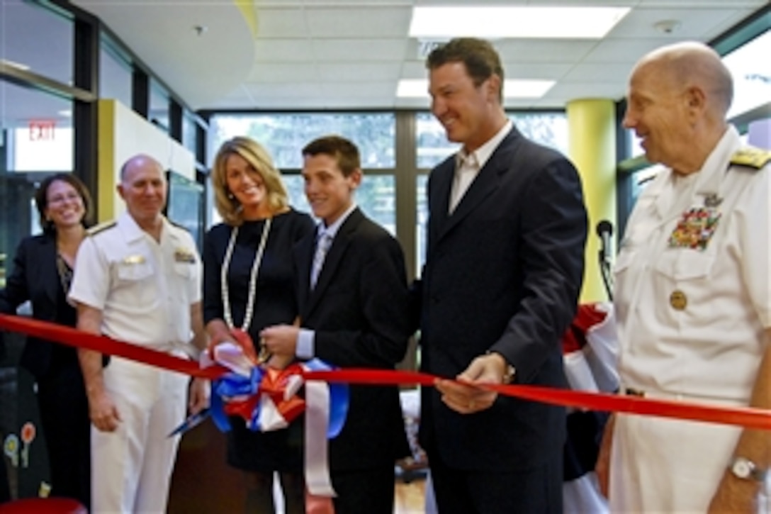Hockey legend Mario Lemieux, his wife, Nathalie, and son, Austin, join Navy Vice Adm. John M. Mateczun, far right, commander of Joint Task Force National Capital Region Medical, and Navy Rear Adm. Matthew Nathan, far left, commander of Walter Reed National Military Medical Center, in cutting the ribbon to officially open Austin's Warrior Playroom in one of the wounded warrior barracks on Naval Support Activity Bethesda, Md., Sept. 7, 2011.