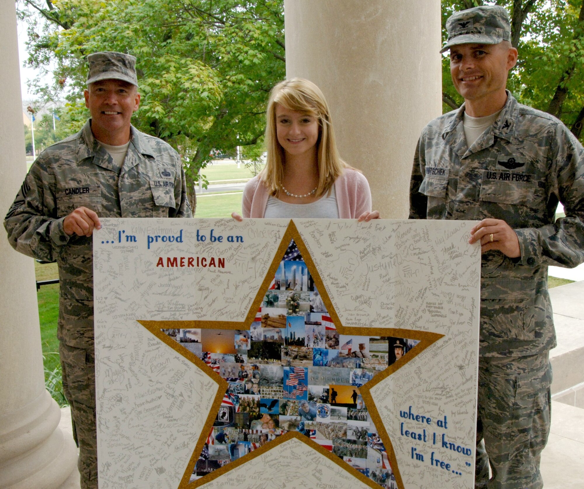 Mackenzie McIntyre, a senior at O'Fallon Township High School, presented Col. Michael Hornitschek, 375th Air Mobility Wing commander, and Chief Master Sgt. Kevin Candler, 375th AMW command chief, with a card of thanks Sept. 9, 2011 signed by more than 500 students from OTHS.  Mackenzie, the daughter of Lt. Col. Jim and Angie McIntyre, 618th Air and Space Operations Center (TACC), said she came up with the idea after watching a documentary about Sept. 11, and in four days designed the card, got approvals from school officials and got signatures in time to present it before the 10th Anniversary of 9/11. (Photo by Karen Petitt)