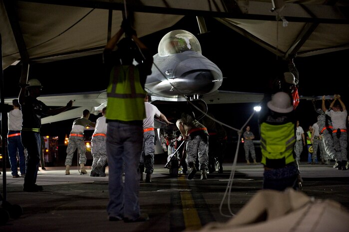 Maintenance and support personnel move an F-16 out from under a collapsed structure at Nellis Air Force Base, Nev. Sept. 9, 2011.  A canopy which provides protection from the elements collapsed when a microburst, a sudden, violent downdraft of air over a small area; hit the base at approximately 5 p.m. Sept. 8.  Eight military members received minor injuries and were treated at the Mike O?Callahan Federal Hospital and all have been released.  In addition to the injured military personnel, vehicles in the area as well as the walls and the concrete pad holding the structure were also damaged.  Thirteen aircraft, including 11 F-16s and two A-10s, were in individual bays were under the structure at the time of the incident.  The incident is under investigation and the full extent of the damage to the aircraft and other resources in the area is currently being assessed. (U.S. Air Force photo/Senior Airman Brett Clashman)