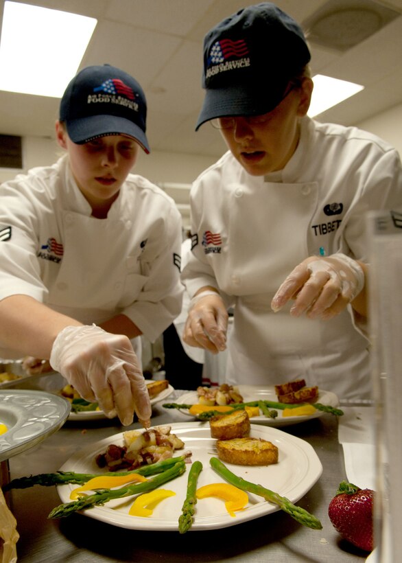 Airmen 1st Class Sarah Ferris and Catherine Tibbetts, 28th Force Support Squadron food services apprentices, put the final touches on their main course during the Ellsworth Iron Chef competition at the Bandit Inn dining facility, Ellsworth Air Force Base, S.D., Aug. 26, 2011. Ferris and Tibbetts were declared the overall winners of the competition. (U.S. Air Force photo/Tech. Sgt. Jerry Fleshman/Released)