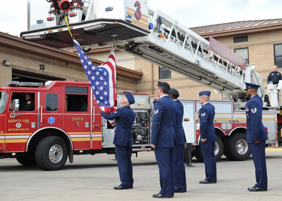 Senior Airman Derald Cox, 22nd Civil Engineer Squadron firefighter, removes an American flag from a Wichita Fire Department fire engine during McConnell’s 2011 Patriot Day Retreat Ceremony at Fire Station 1 Sept. 7, 2011, McConnell Air Force Base, Kan. First responders from the 22nd Civil Engineer Squadron, 22nd Security Forces Squadron and 22nd Medical Group joined their civilian counterparts for the ceremony to honor those who lost their lives and the continuing efforts of military and civilian first responders at home and abroad. (U.S. Air Force photo/Airman 1st Class Katrina M. Brisbin)