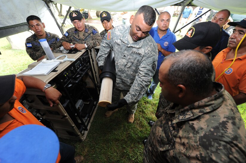 Staff Sgt. Vladimir Ramirez, Army Forces armorer, shows Honduran first responders how to replace a filter on the water purification system of the Pre-positioned Expeditionary Assistance Kit, or PEAK Aug. 31, 2011, at Soto Cano Air Base, Honduras. The PEAK is a modular system that provides potable water, communications and power generation, and information sharing to first responders immediately following a disaster event. (U.S. Air Force photo/Tech. Sgt. Matthew McGovern)