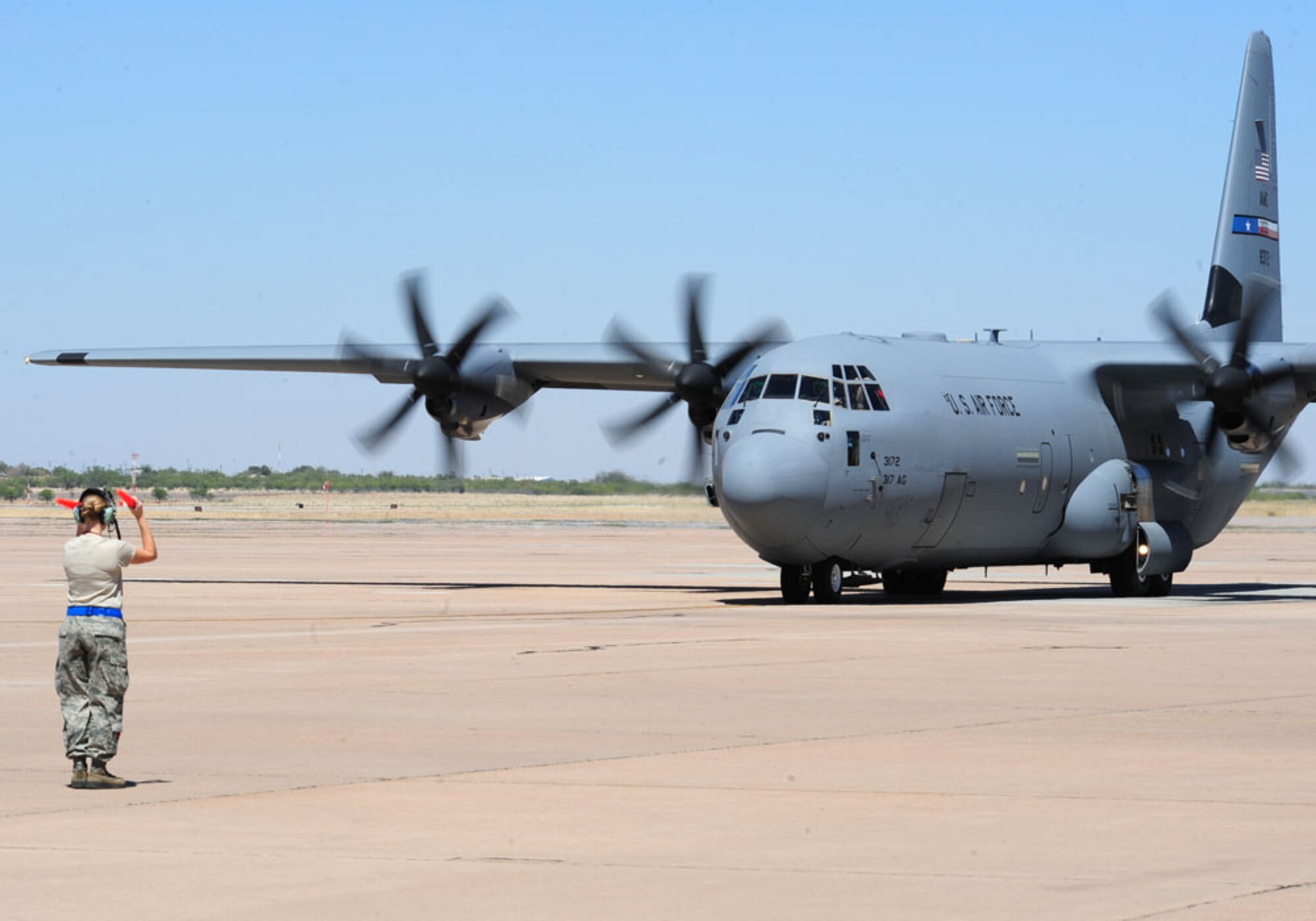 A Dyess crew chief marshals a C-130J Sept. 6, 2011 taking off for deployment for the first time from Dyess AFB, Texas. The aircraft is deploying in support of Overseas Contingency Operations in Southwest Asia. (U.S. Air Force photo by Airman 1st Class Peter Thompson/ Released)