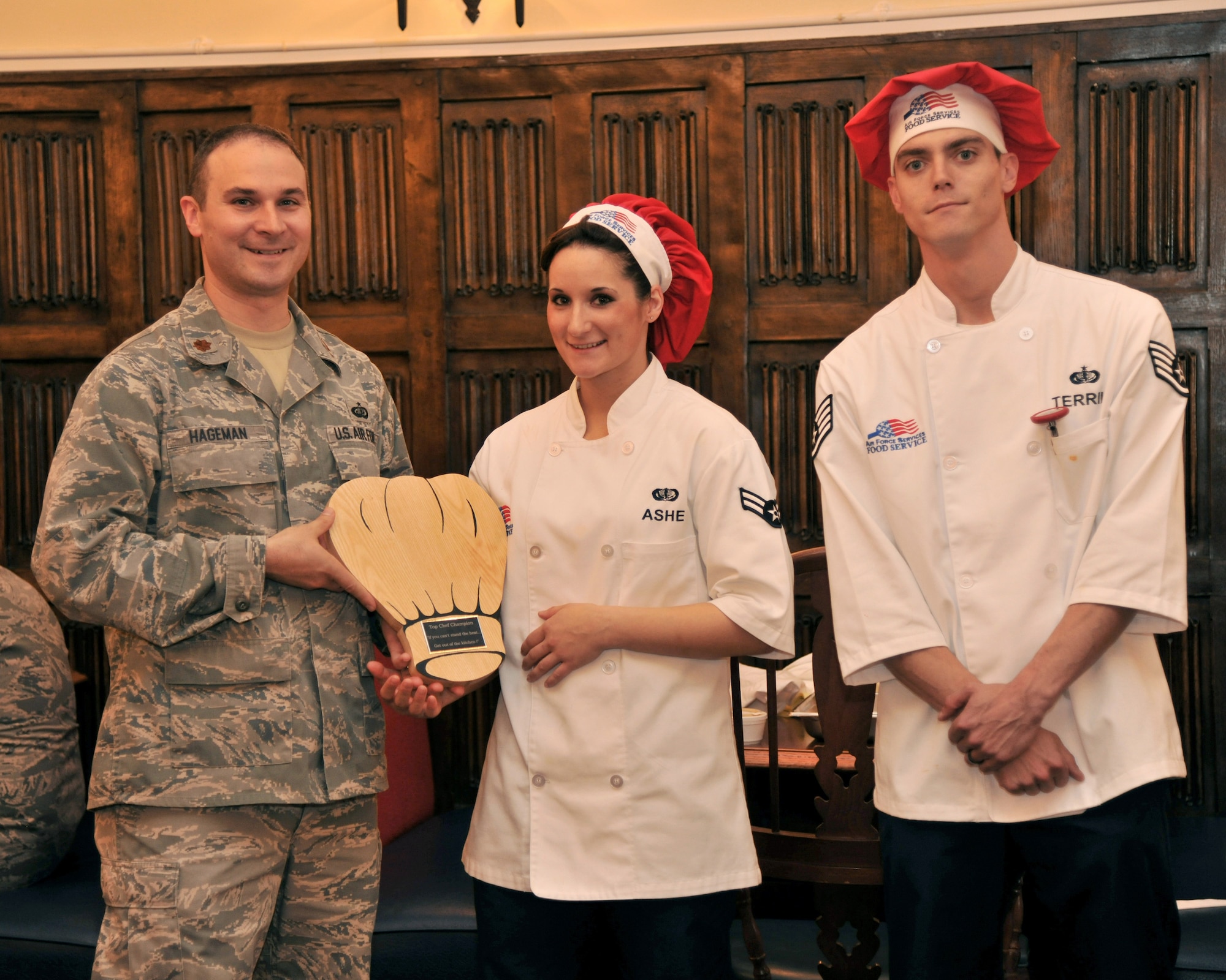 RAF MILDENHALL, England -- Maj. Adrian Hageman, 100th Force Support Squadron commander, presents the Top Chef Competition award to Airman 1st Class Jessica Ashe and Staff Sgt. Derek Terrill at the Gateway Dining Facility here Sept. 8, 2011. Three teams had 90 minutes to prepare, cook and serve five different dishes. The winning team was selected based on taste, texture and presentation of their dish. (U.S. Air Force photo by Senior Airman Jerilyn Quintanilla)  