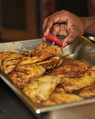 RAF MILDENHALL, England -- Airman 1st class Brandon Castillo, 100th Force Support Squadron, checks the temperature of chicken during the Top Chef Competition at the Gateway Dining Facility here Sept. 8, 2011. The three teams competing in this friendly competition prepared five dishes and were judged on taste, texture and presentation. (U.S. Air Force photo by Senior Airman Jerilyn Quintanilla)