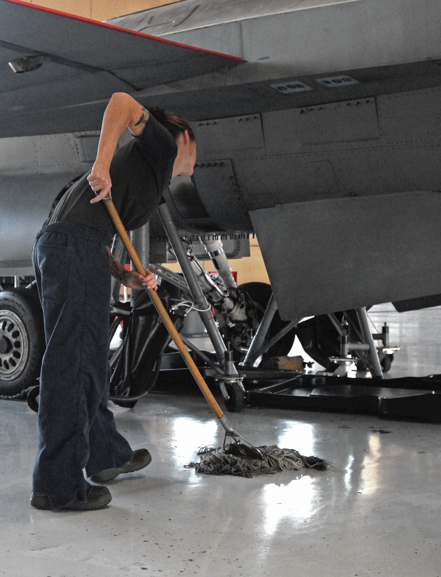 Airman 1st Class Kelsey Henry, 309th Aircraft Maintenance Unit "house mouse", cleans Hangar 914, Luke Air Force Base, Ariz.  Mopping is one of 13 items on the Hangar Inspection Checklist completed daily.  (U.S. Air Force photo by Senior Airman Melanie Holochwost)