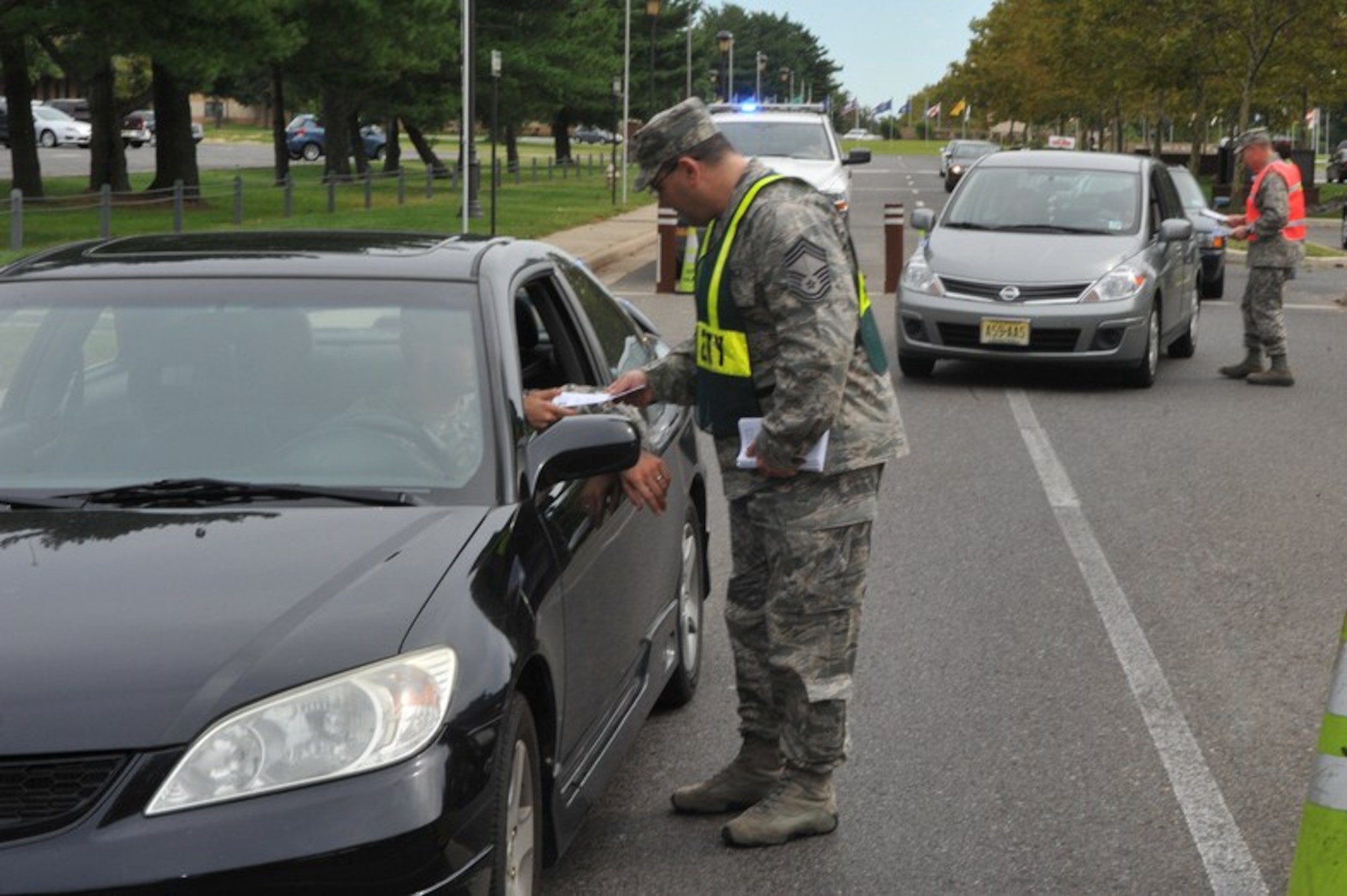 Chief Master Sgt. Sam D'Urso, 305th Operations Support Squadron, hands out a "Critical Days of Summer" brochure to end the 101 days of summer which encourages members of the joint base community to be safe.  Various commanders and other senior leadership stood at the main gate from 3 to 5 p.m. Sept. 1. (U.S. Air Force Photo by Jack D Neith/Released)