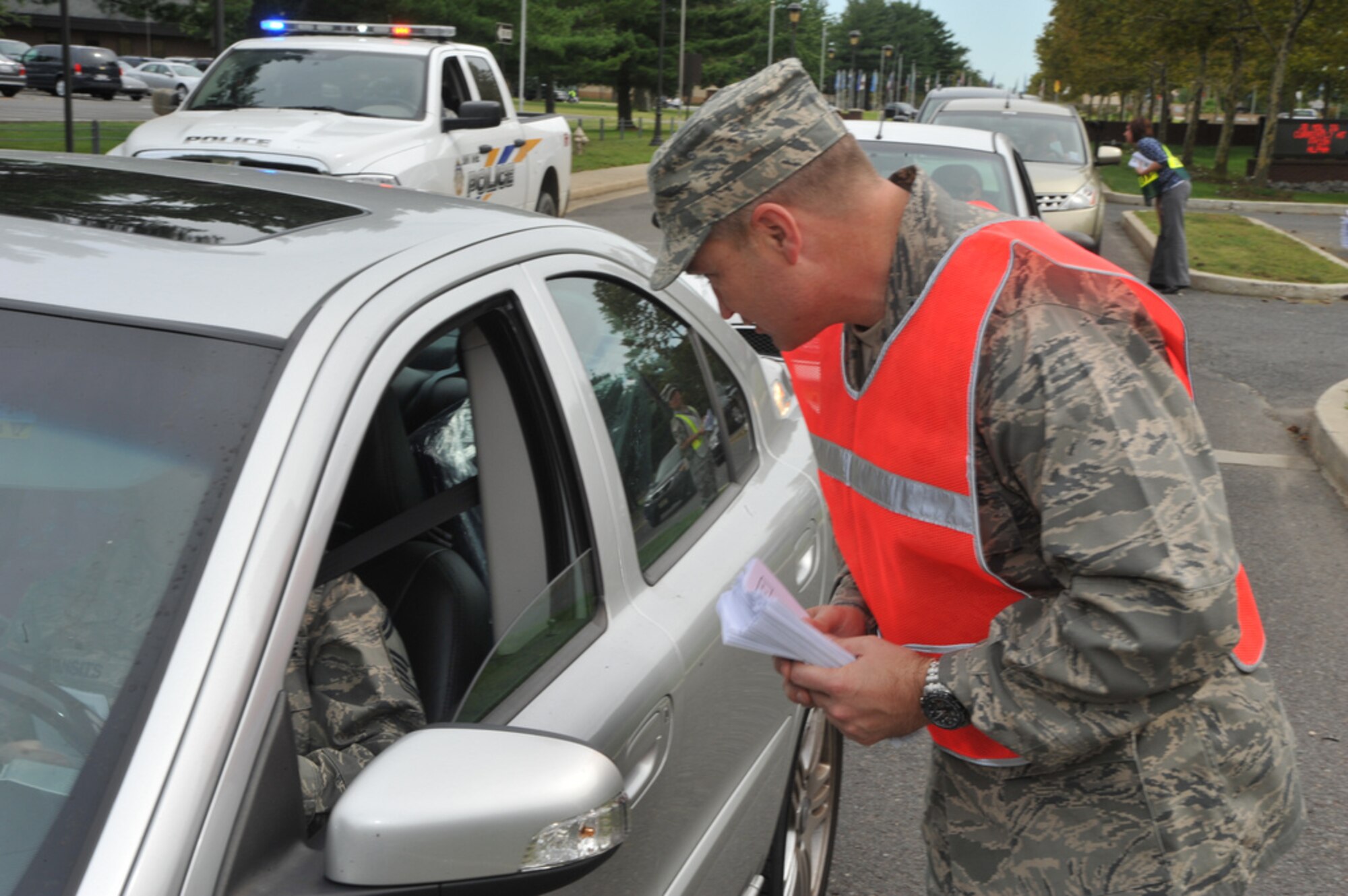 Col. Dale Anderson, 305th Air Mobility Wing vice commander, hands out a "Critical Days of Summer" brochure to end the 101 days of summer which encourages members of the joint base community to be safe.  Various commanders and other senior leadership stood at the main gate from 3 to 5 p.m. Sept. 1. (U.S. Air Force Photo by Jack D Neith/Released)