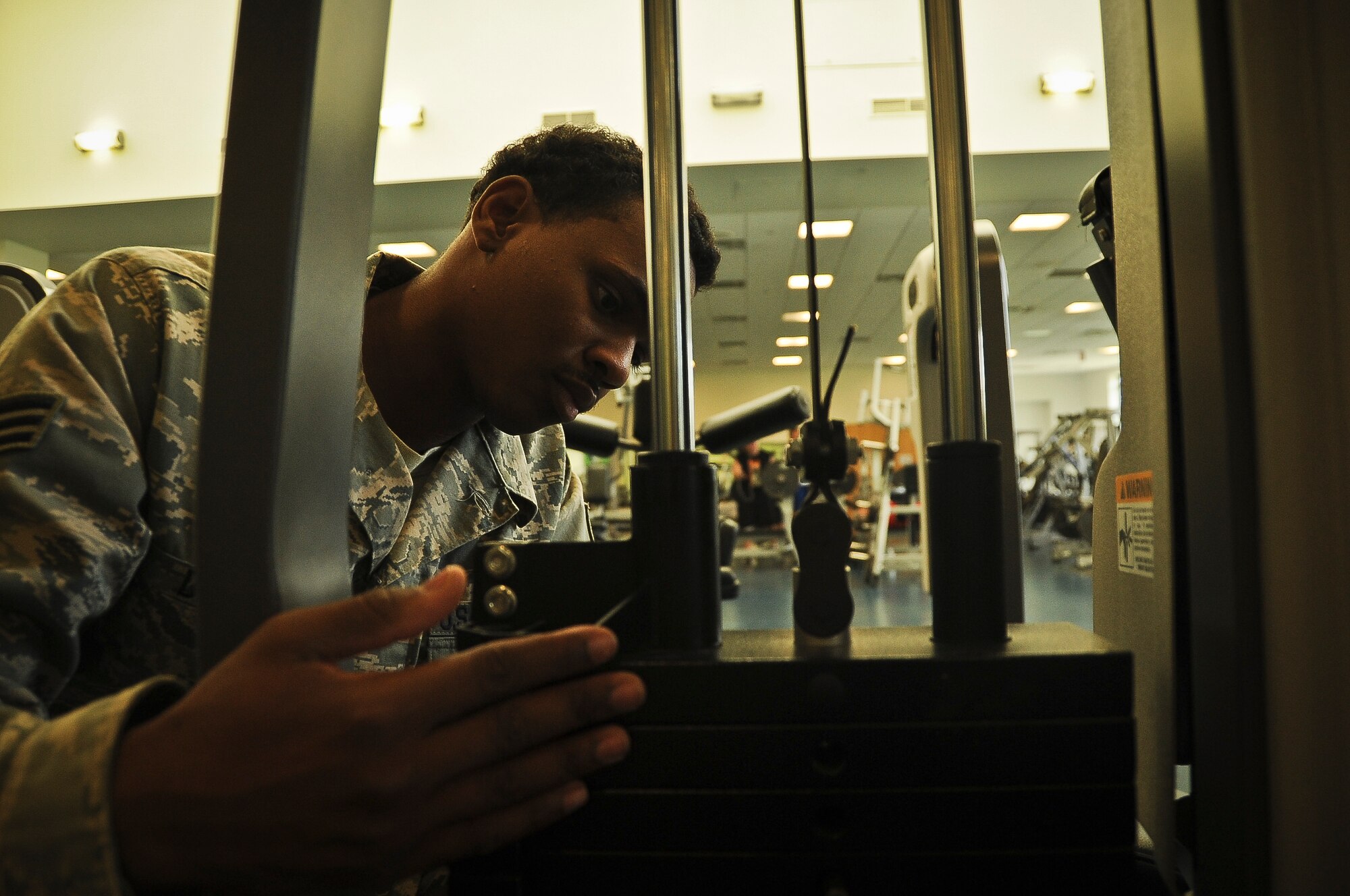Senior Airman Corey Doss, 87th FSS fitness apprentice, inspects an abdominal crunch machine at the McGuire Fitness and Sports Center Aug. 30. Doss is required to wipe the equipment down throughout the day and test each piece to make sure it is safe and working properly. (U.S. Air Force photo by Airman 1st Class Dennis Sloan/Released)