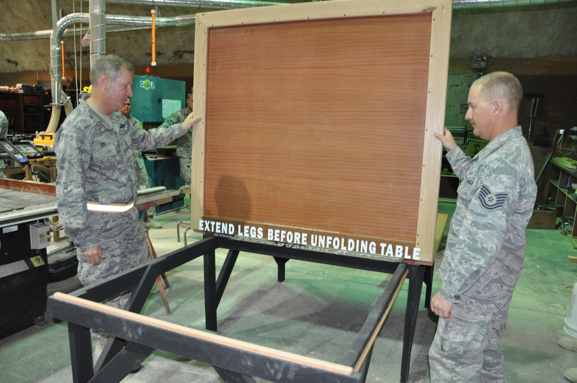 Colonel Michael Zick, 386th Air Expeditionary Wing commader recieves a brief from Technical Sgt. Steve Vernig, 386th Expeditionary Civil Engineer Squadron structural craftsman, on the flag table built for the folding and ironing of the American flag. (U.S. Air Force photo by Senior Airman Rachelle Elsea)