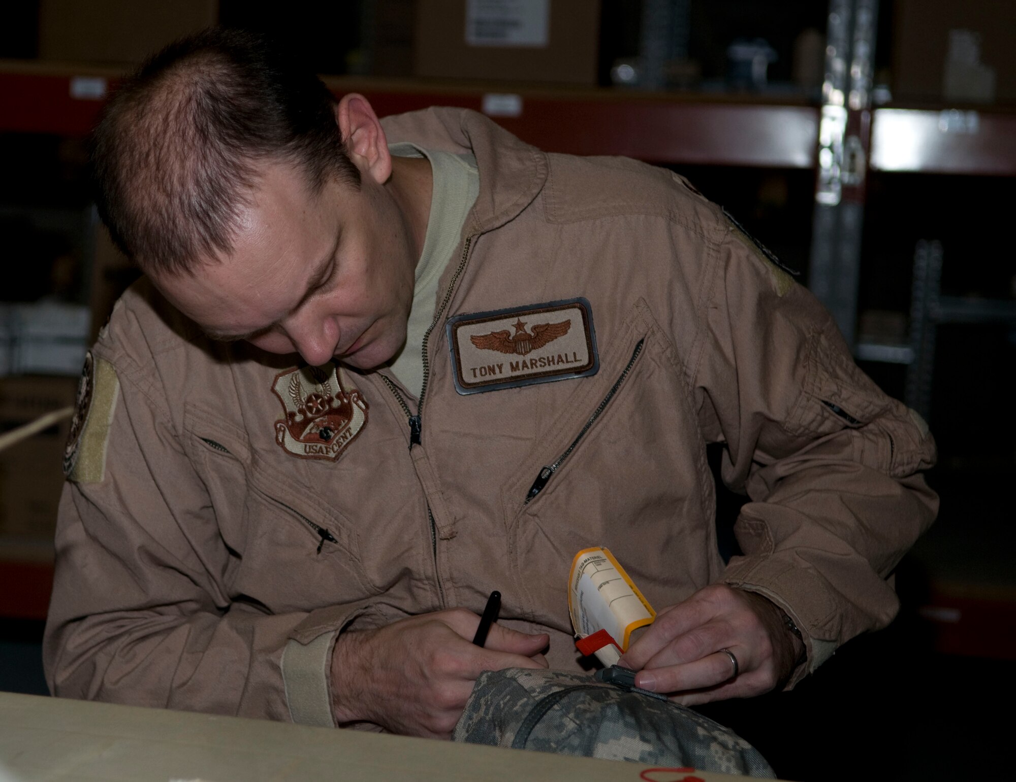Maj. Tony Marshall, a volunteer from the 379th Expeditionary Operations Group, pulls off the red tab that signifies an unused individual first aid kit, to check for expired items, Aug. 24.  Marshall is deployed from Little Rock Air Force Base, Ark.  (U.S. Air Force photo/Senior Airman Eric Summers Jr.)