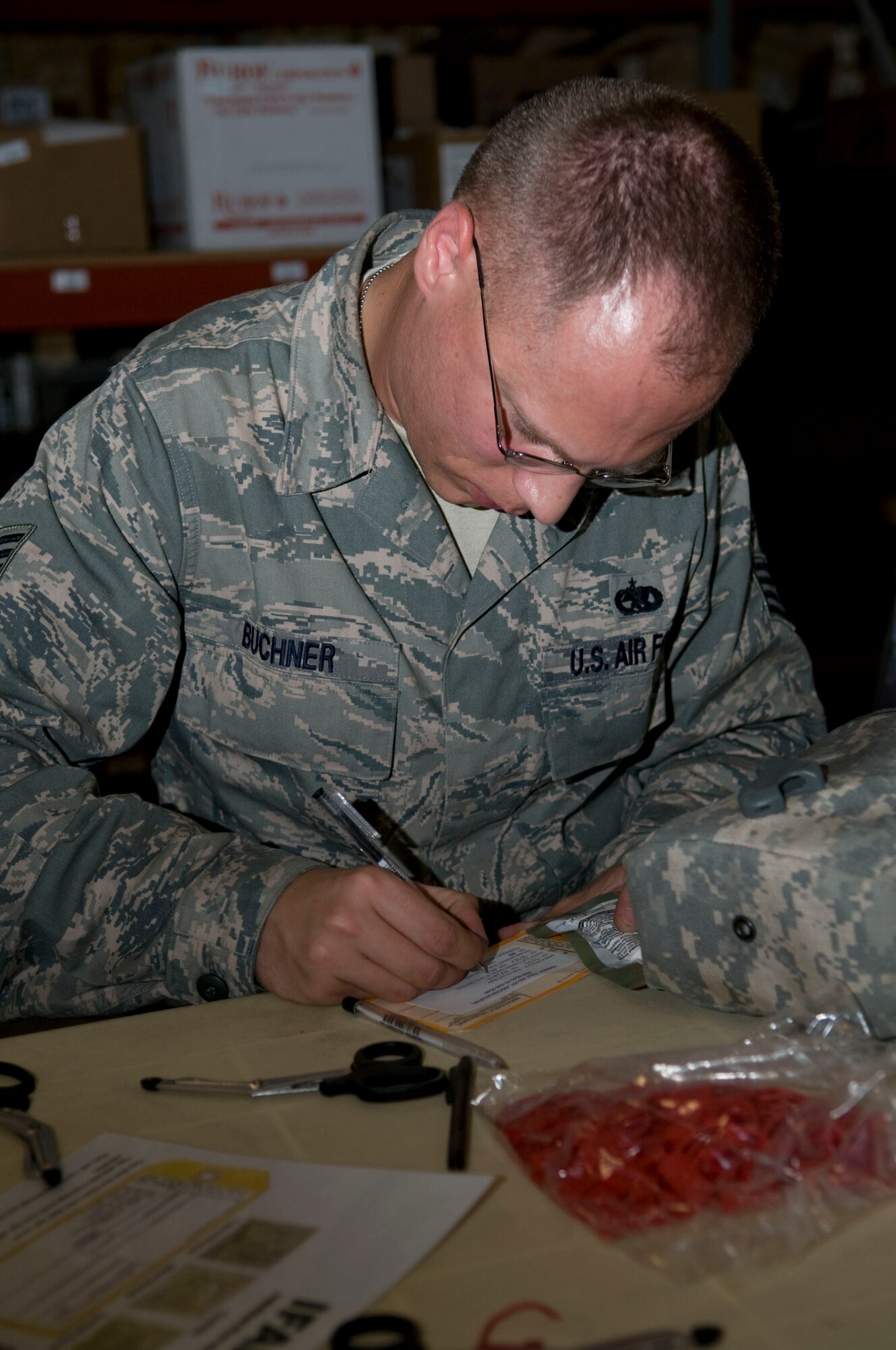 Staff Sgt. Stephen Buchner, a volunteer from the 379th Expeditionary Maintenance Squadron, fills out a new tag for an individual first aid kit, listing the expiration date of the contents, Aug. 24.  Buchner is deployed from Joint Base McGuire-Dix-Lakehurst, N.J. (U.S. Air Force photo/Senior Airman Eric Summers Jr.)