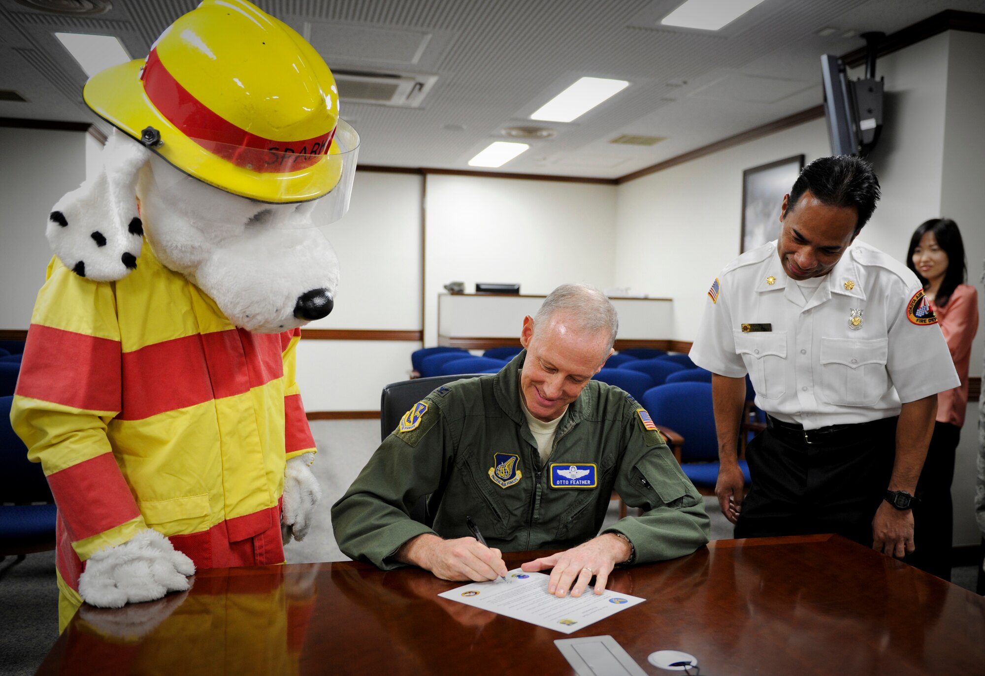 Col. Otto Feather, 374th Airlift Wing commander, signs a proclamation letter declaring October 8-15 as fire prevention week here September 09, 2011, before an audience of Sparky the Fire Dog and other members of the Yokota Fire Department. During fire prevention week, the Yokota Fire Department will sponsor activities across the base to educate children and their parents on fire prevention and detection. (U.S. Air Force photo/Staff Sgt. Stacy Moless)