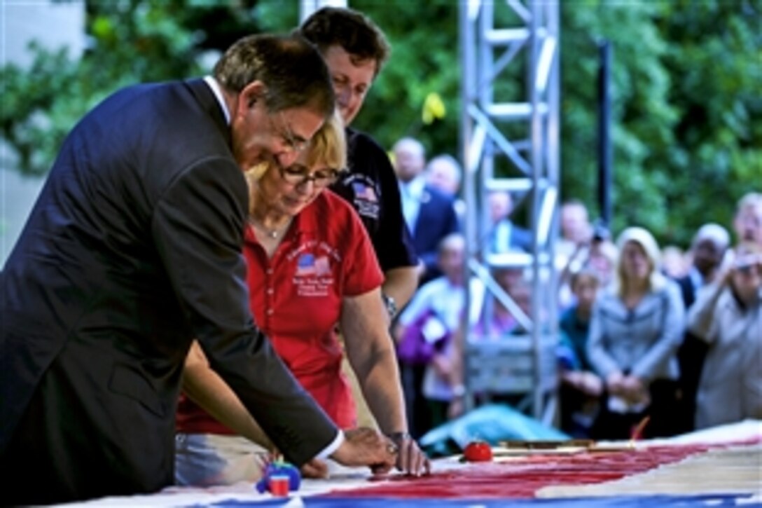 Defense Secretary Leon E. Panetta and Defense Department employees gather in the Pentagon courtyard, Sept. 9, 2011, to add stitches to the flag that flew over the World Trade Center during the 9/11 terrorist attacks.